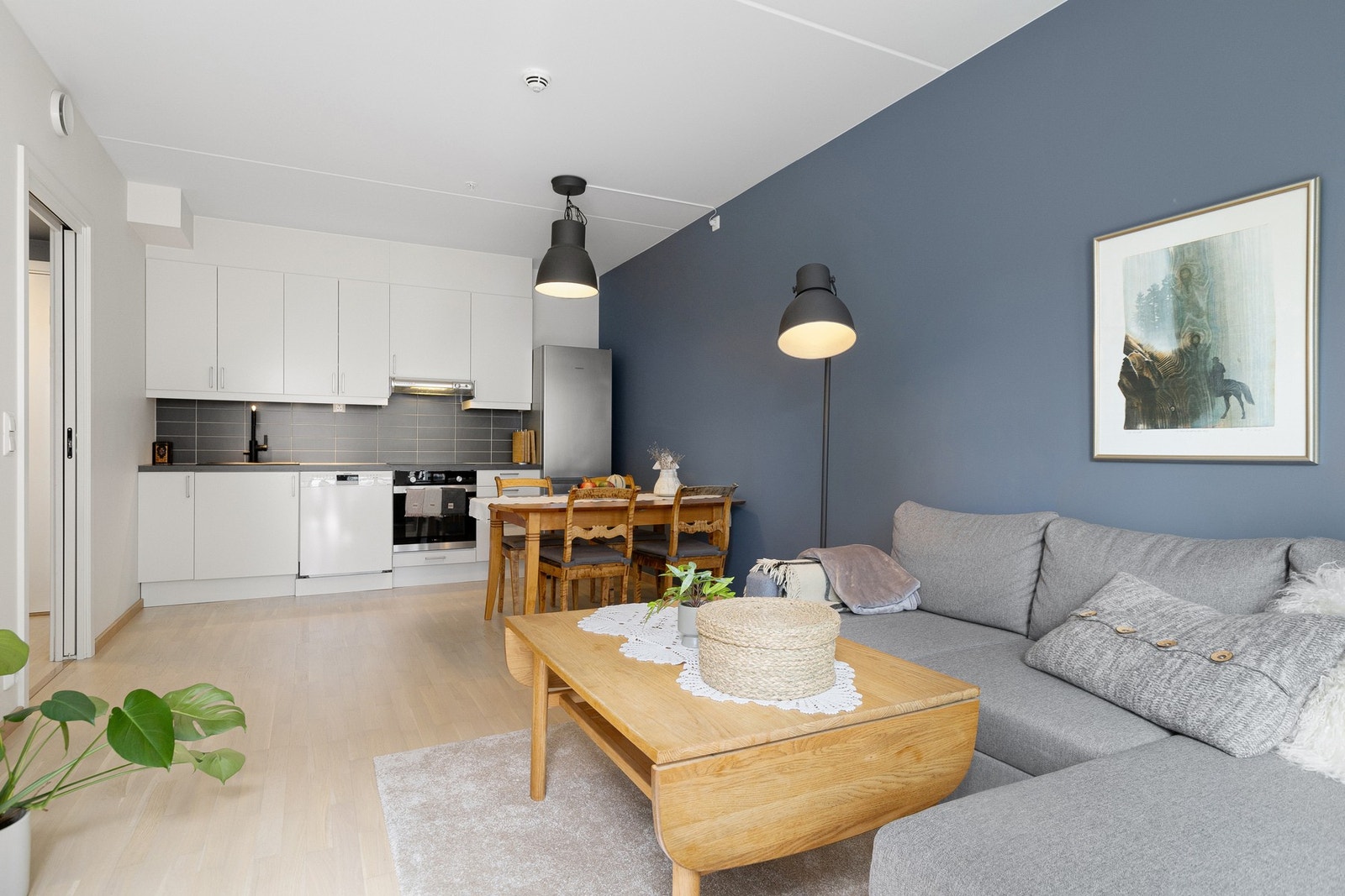 Leiligheten har en åpen stue- og kjøkkenløsning og er kjernen i leiligheten. Det sosiale allrommet har naturlige soner for møblering. Galleribilde