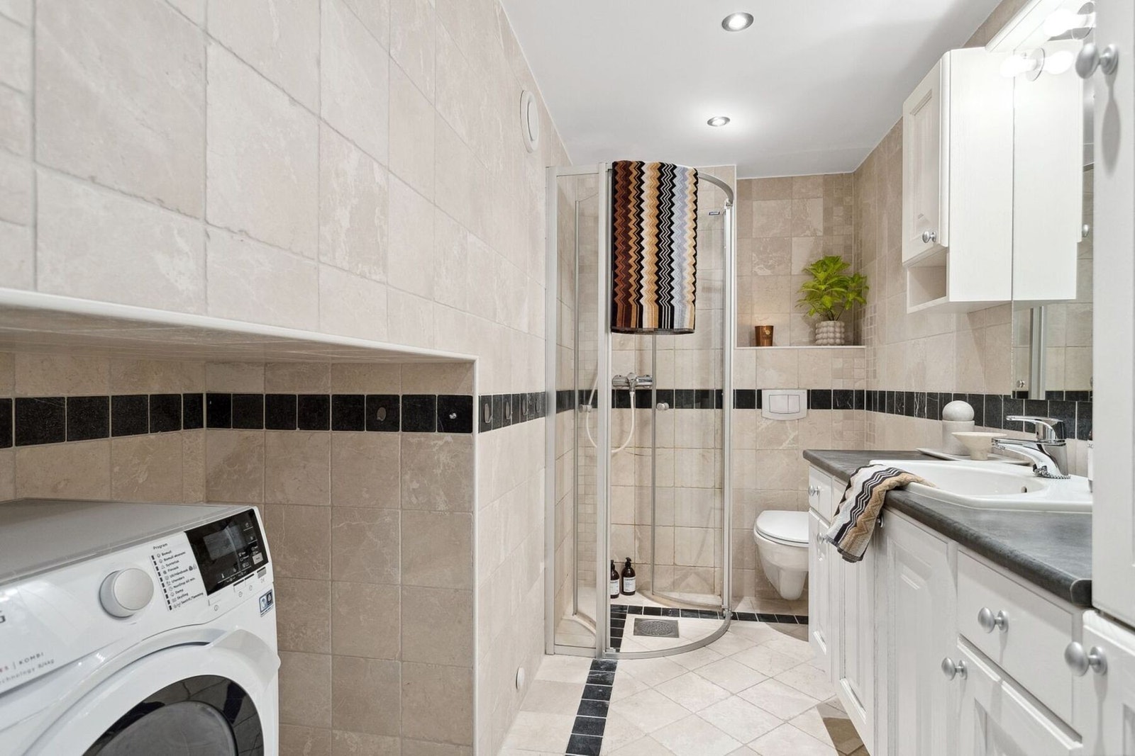 Baderommet inneholder vegghengt wc, servant med over og underskap, dusjhjørne og opplegg for vaskemaskin. Galleribilde