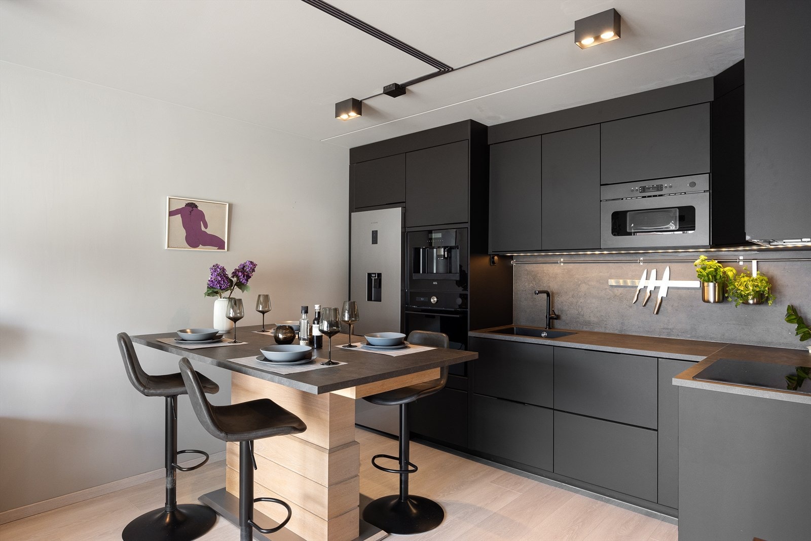 Kjøkkenet har sorte glatte fronter, laminert plate mellom benkeplate og overskap, benkeplaten er i laminat, samt nedfelt oppvaskkum med ettgreps svingbart blandingsbatteri. Galleribilde