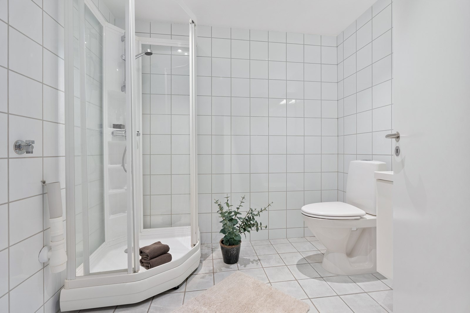 Badet er helfliset med varme i gulvet. Det inneholder et praktisk dusjkabinett, toalett, baderomsinnredning med speil over, samt plass og opplegg for vaskemaskin. Galleribilde