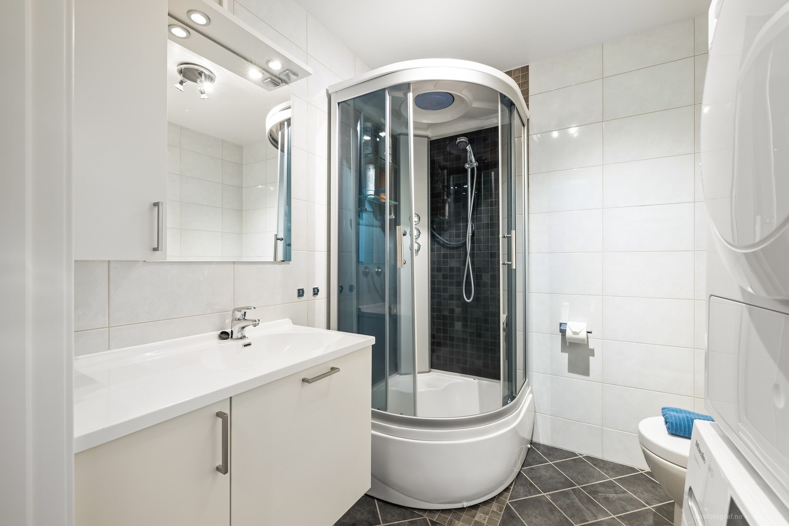 Badet har flislagte overflater og varme i gulv. Badet er innredet med toalett, servant og dusjkabinett. Galleribilde