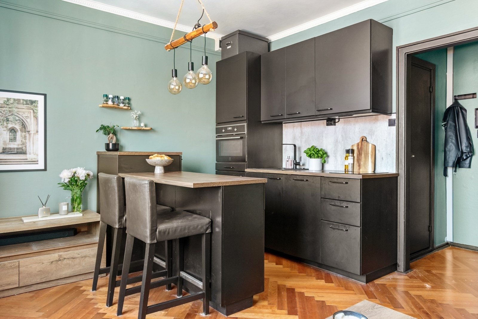 Det er fiskebensparkett på gulv, rosetter og stukkatur. Veggene er malt i en delikat farge som står i stil med kjøkkenet. Galleribilde