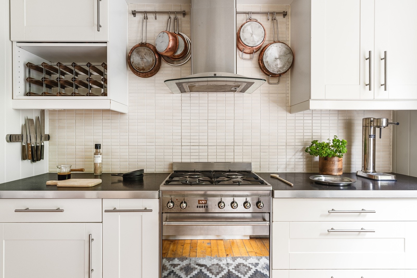 Delikat kjøkkeninnredning med hvite profilerte fronter, to glasskap og laminat benkeplate med nedfelt vaskekum av stål. Galleribilde