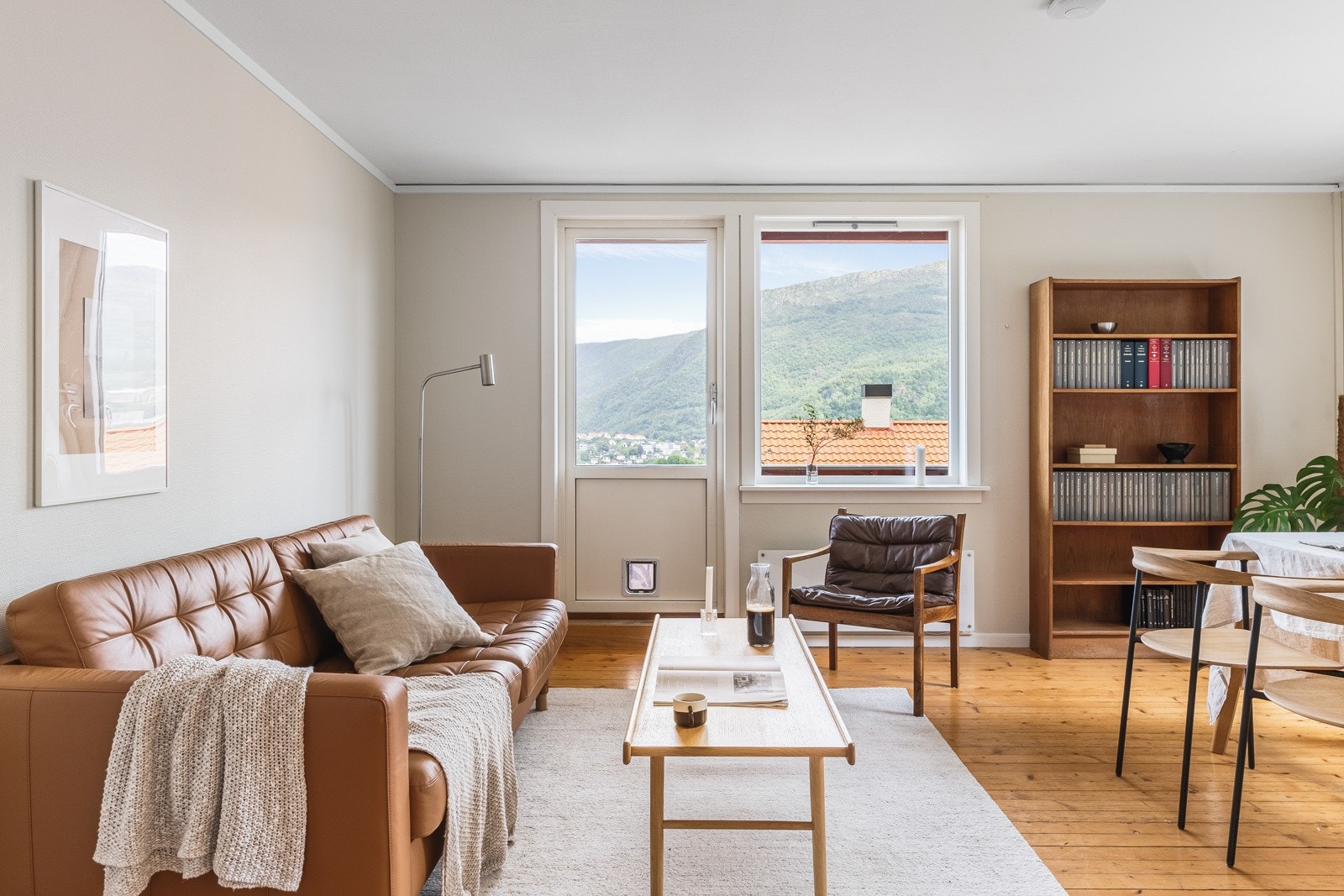 Leilighetens stue har rikelig med lysinnslipp som komplimenterer lune farger på vegger og det flotte tregulvet. Galleribilde