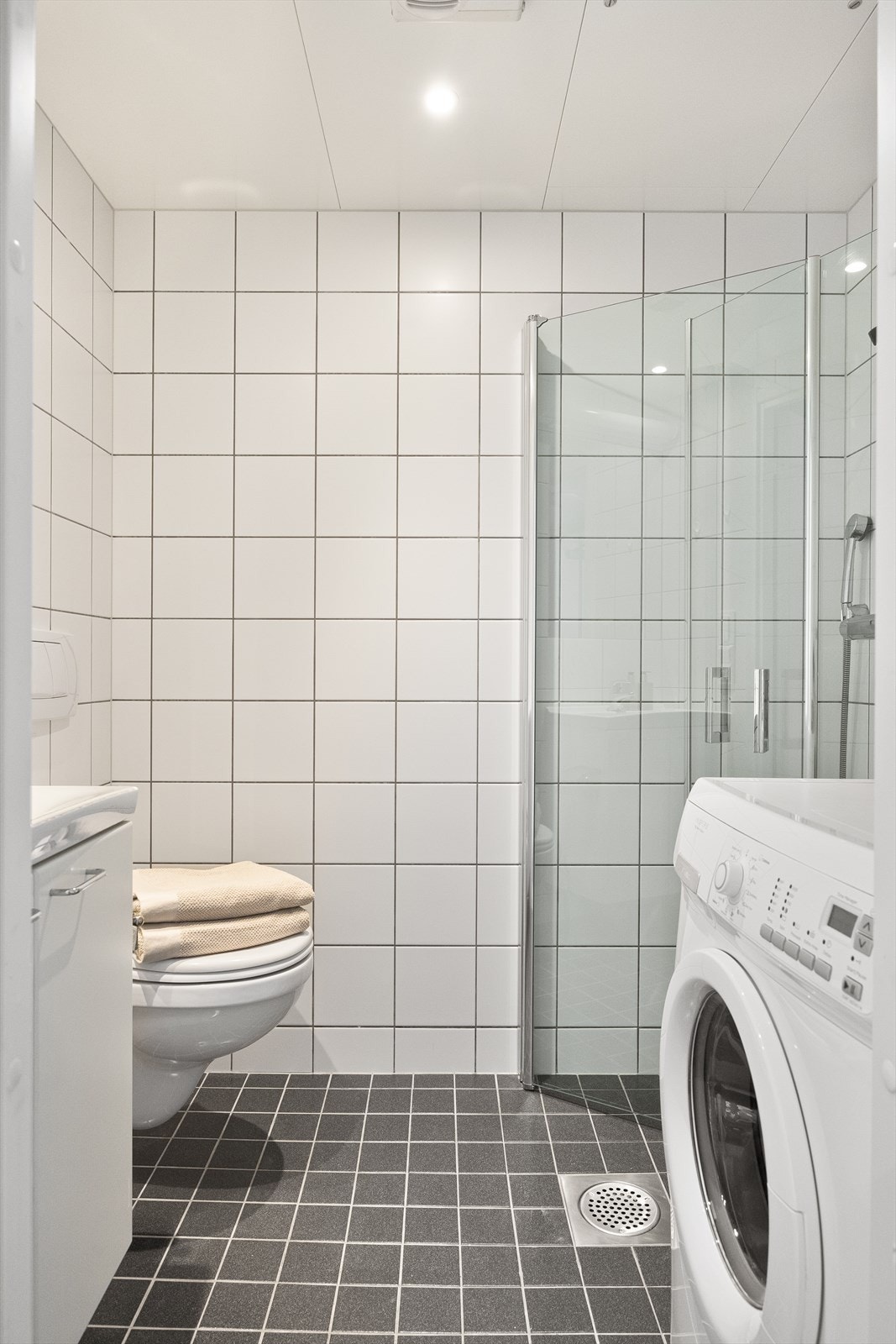 Badet er flislagt og utstyrt med downlights i taket, som gir rommet en moderne og behagelig belysning. Den elektriske gulvvarmen sørger for en komfortabel temperatur gjennom hele året. Galleribilde