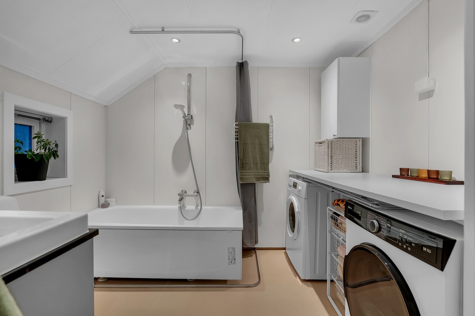 Badet i andre etasje er en kombinasjon av bad og vaskerom. Baderomsinnredningen består av servant med underskap og badekar. Det er opplegg for vaskemaskin. Galleribilde