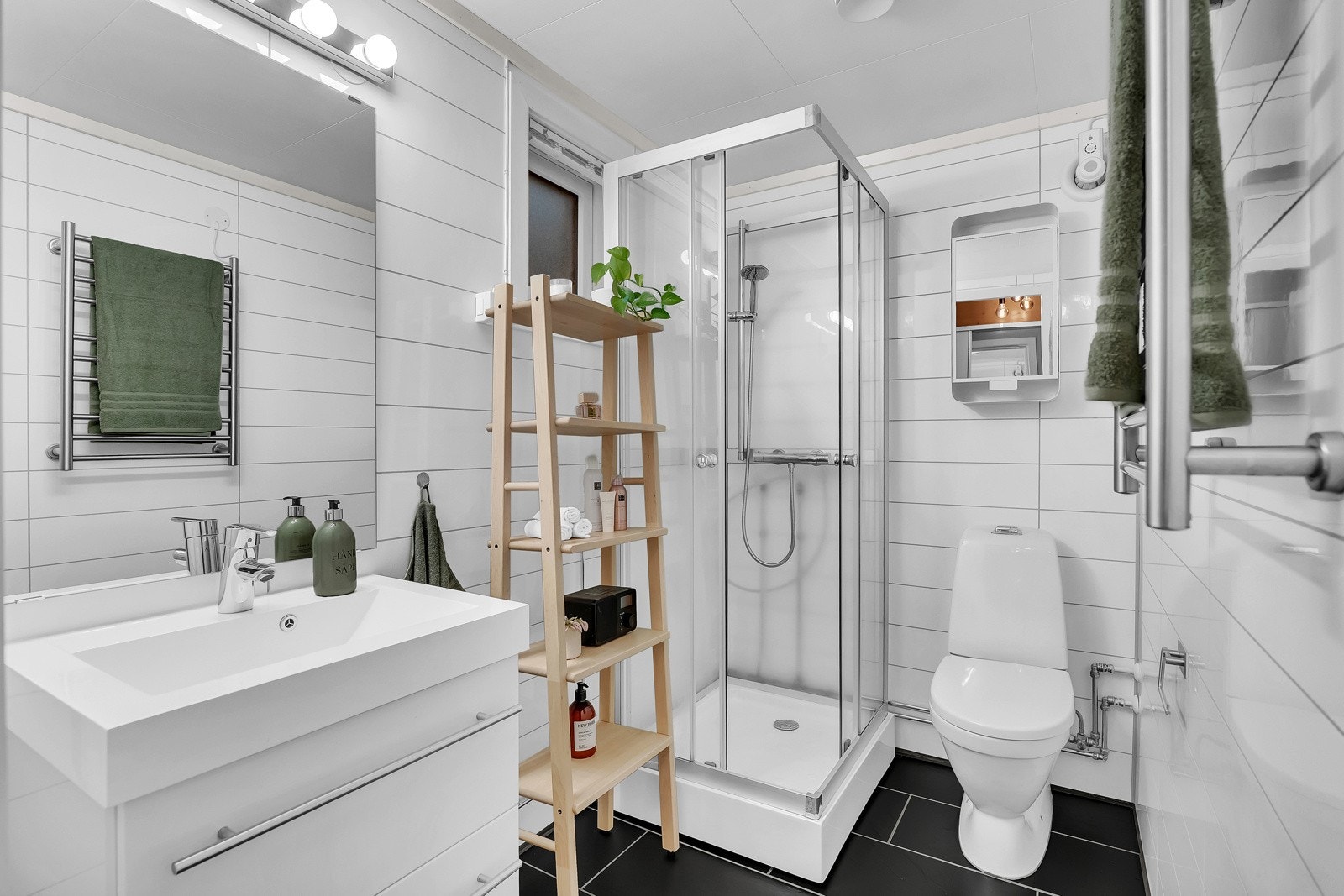 Badet i første etasje består av servant med underskap, speil, dusjkabinett og gulvmontert toalett. Galleribilde