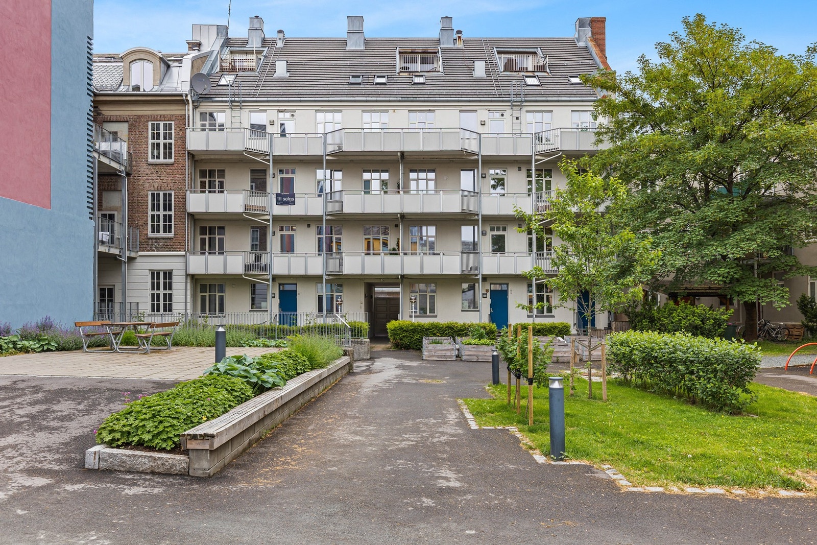 Hyggelig gårdsrom med beplantning, lekeplass og benker. Galleribilde