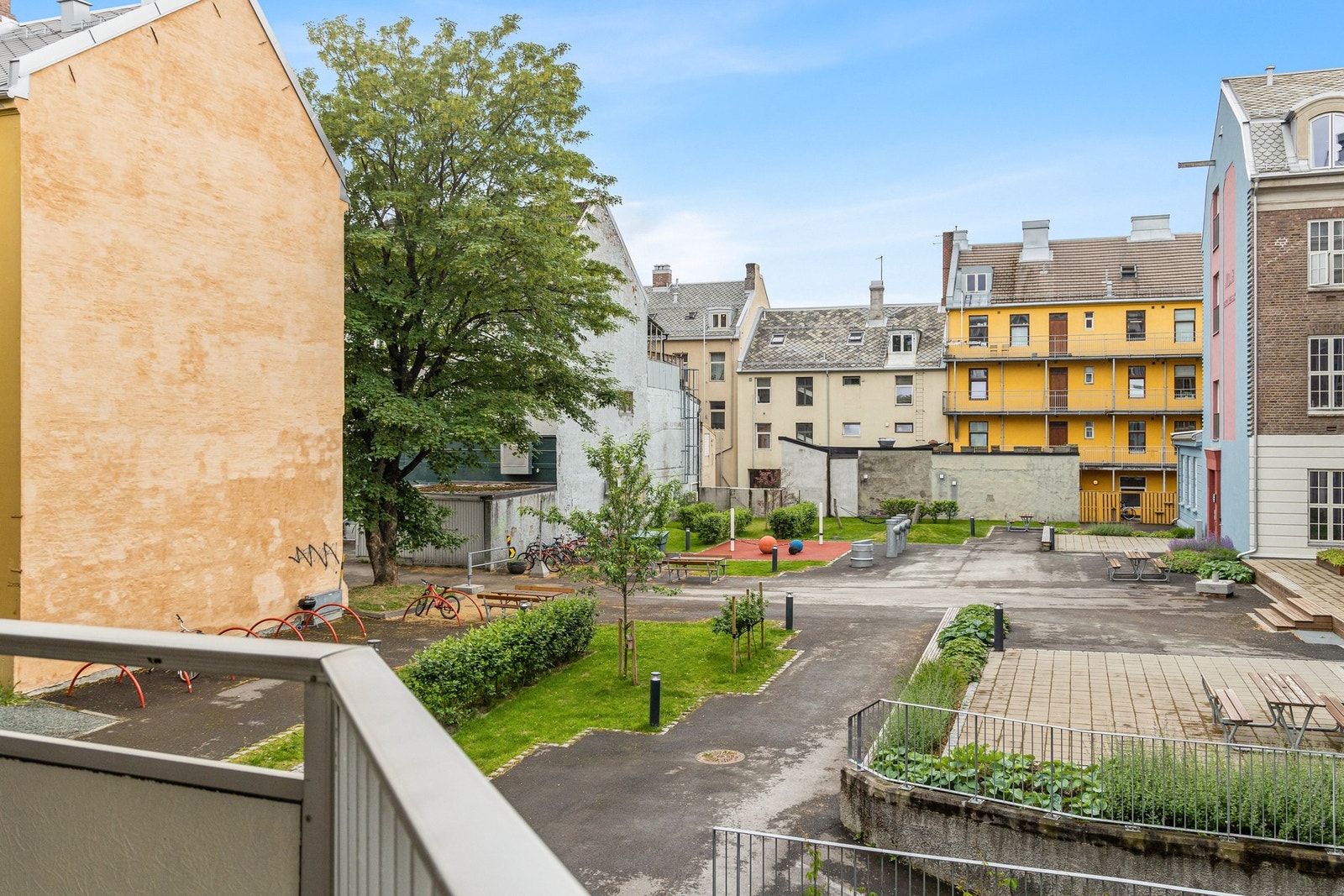 Hyggelig gårdsrom med beplantning, lekeplass og benker. Galleribilde