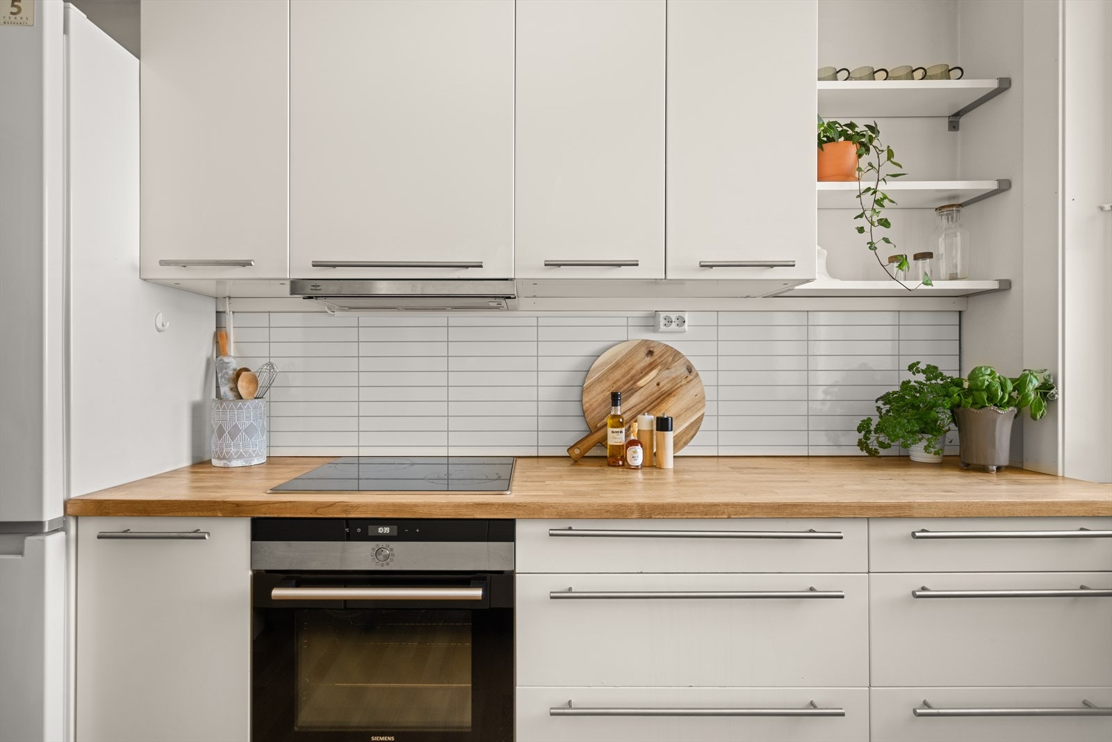 Kjøkkeninnredning fremstår med glatte fronter. Heltre benkeplate med oppvaskkum og 1-greps blandebatteri. Lys under overskap, ventilator med kullfilter. Galleribilde