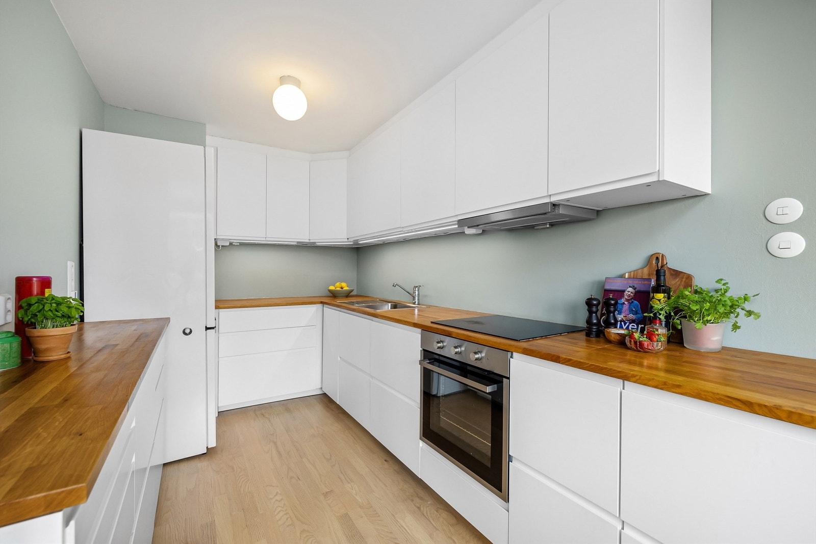 Stilrent IKEA-kjøkken fra 2017 der kjøkkeninnredning har glatte lyse fronter og benkeplate i eik Galleribilde