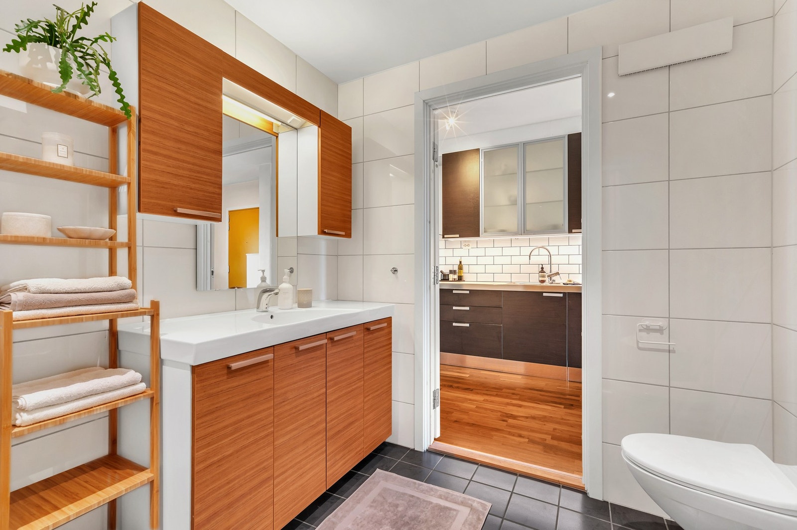 Baderommet utstyrt med varmekabler i gulv, vegghengt toalett, innredning med servant og opplegg for vaskemaskin. Galleribilde