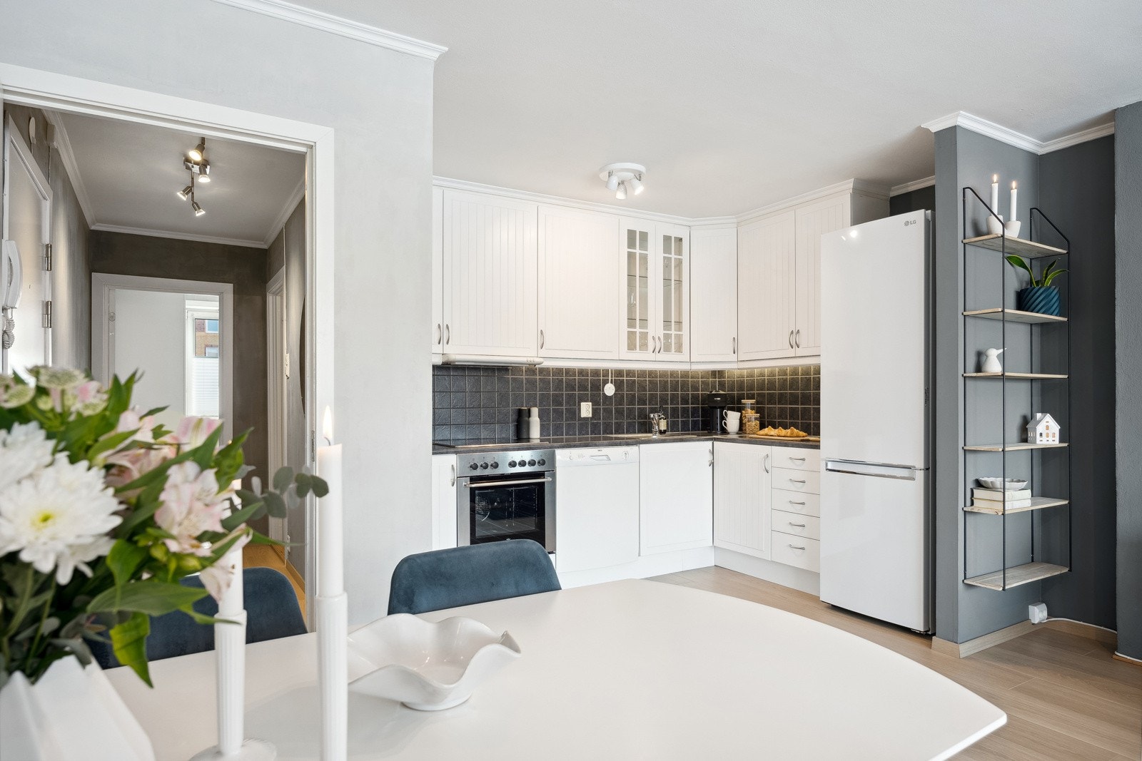 Kjøkkenet fremstår lyst og moderne med hvite kjøkkenfronter og delvis integrerte hvitevarer. Galleribilde