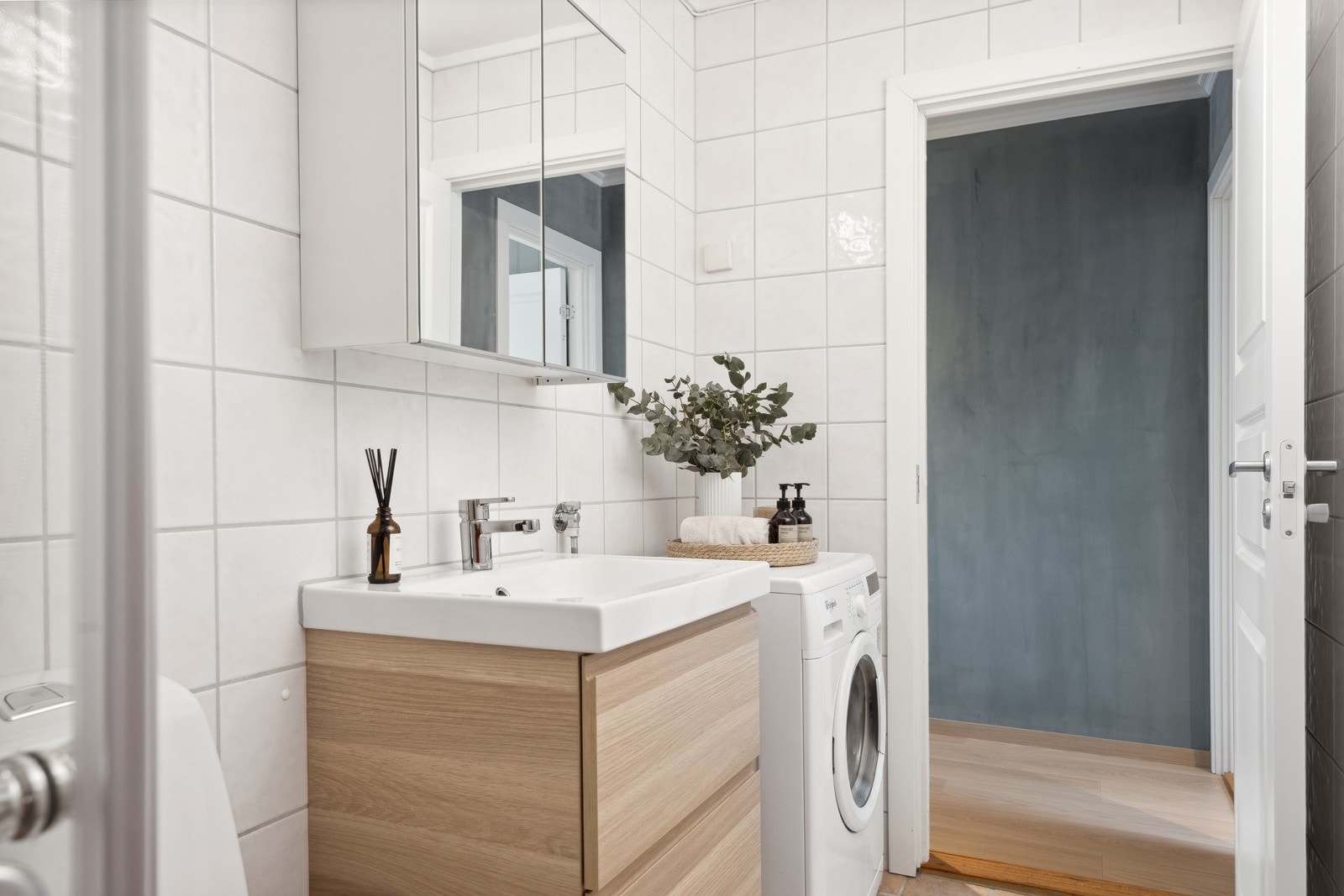 Badet er utstyrt med dusjhjørne, servant med skuffeseksjoner, speilskap, toalett og opplegg for vaskemaskin. Galleribilde