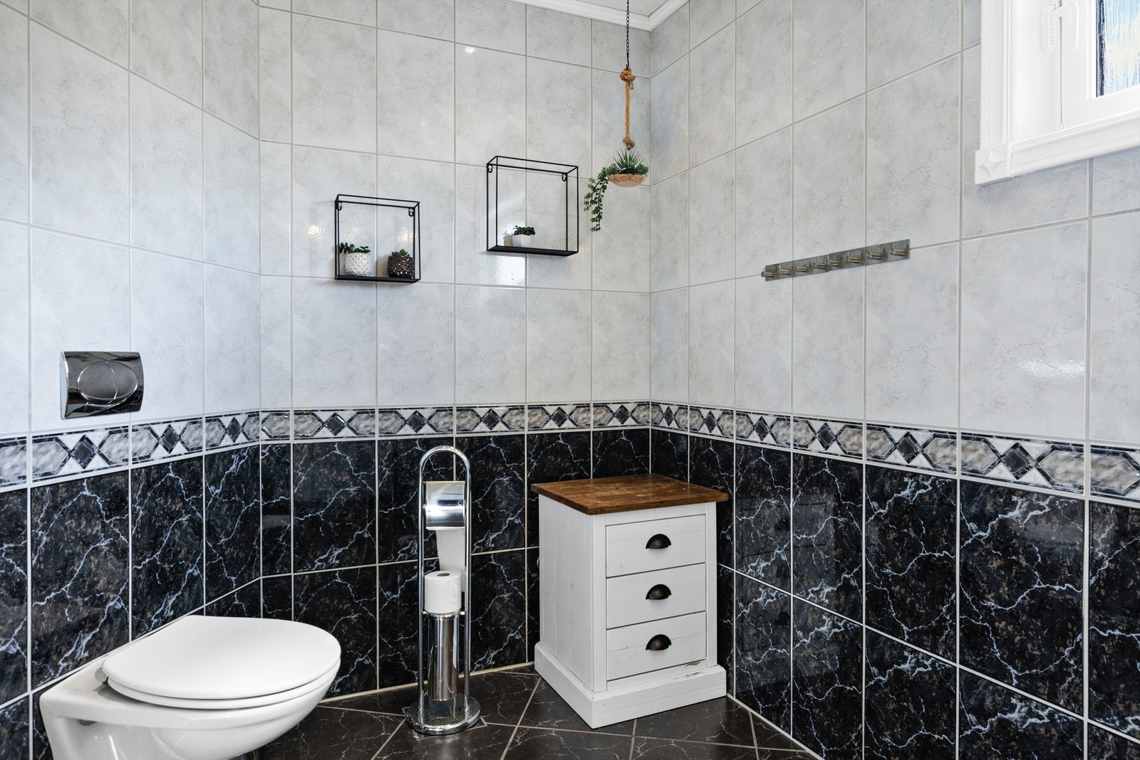 Badet er innredet med baderomsinnredning med heldekkende servant, veggmontert toalett og dusjhjørne Galleribilde