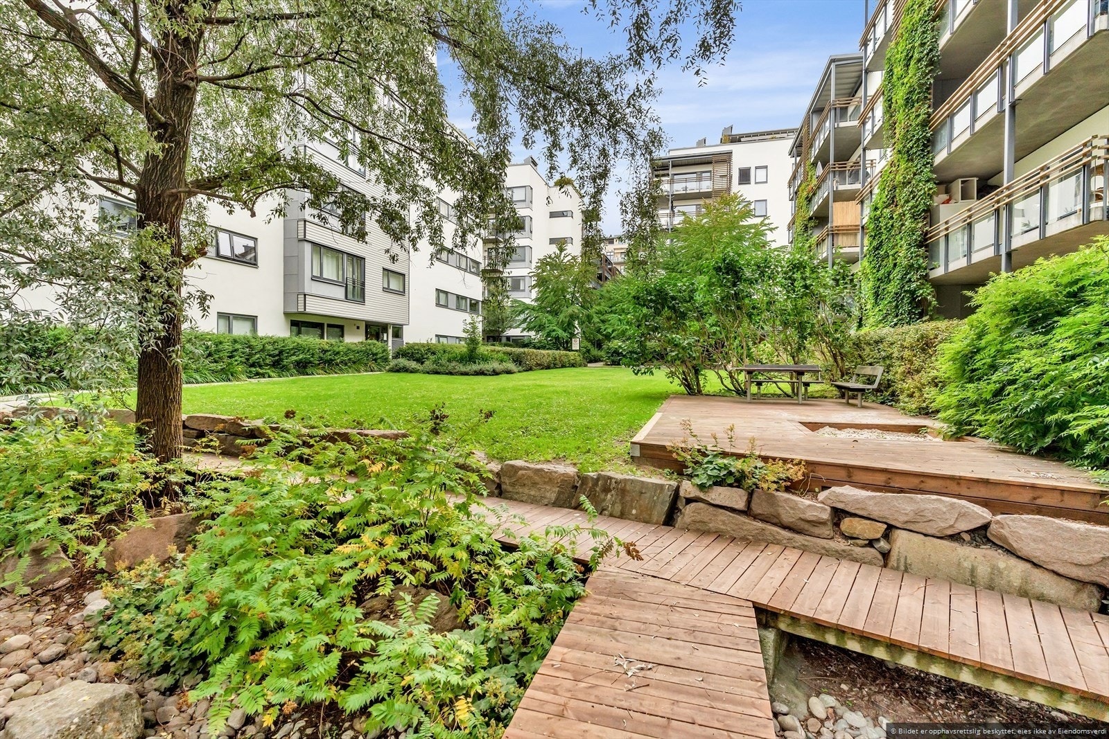 Tomten er opparbeidet med asfalterte interne internveier, plen, beplantningersittegrupper m.m. Galleribilde