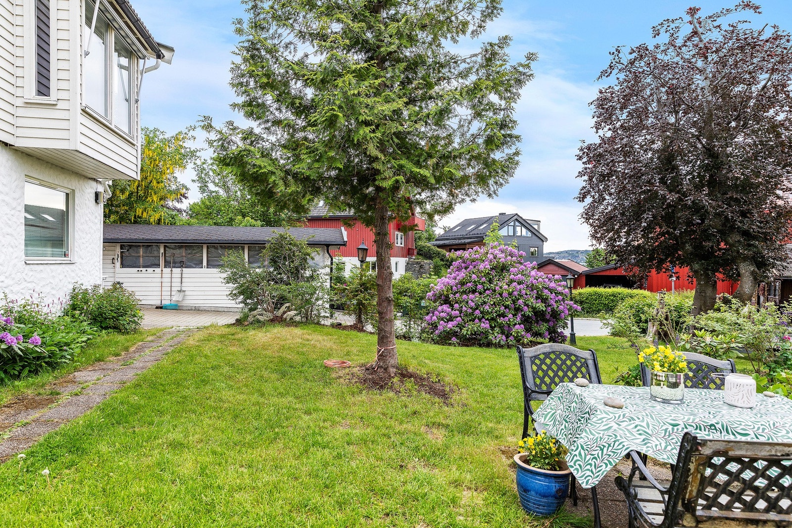 Pent opparbeidet hage med vakker beplantning, blomster, og busker som gir et vakkert bilde gjennom sommeren. Galleribilde