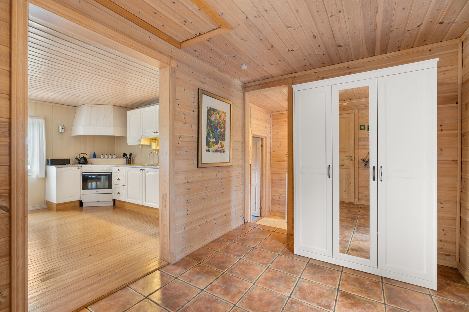 Lyst og romslig. Entréen har flislagt gulv. Herfra er det en liten trapp ned til et ekstra rom, med videre inngang til bad. Galleribilde