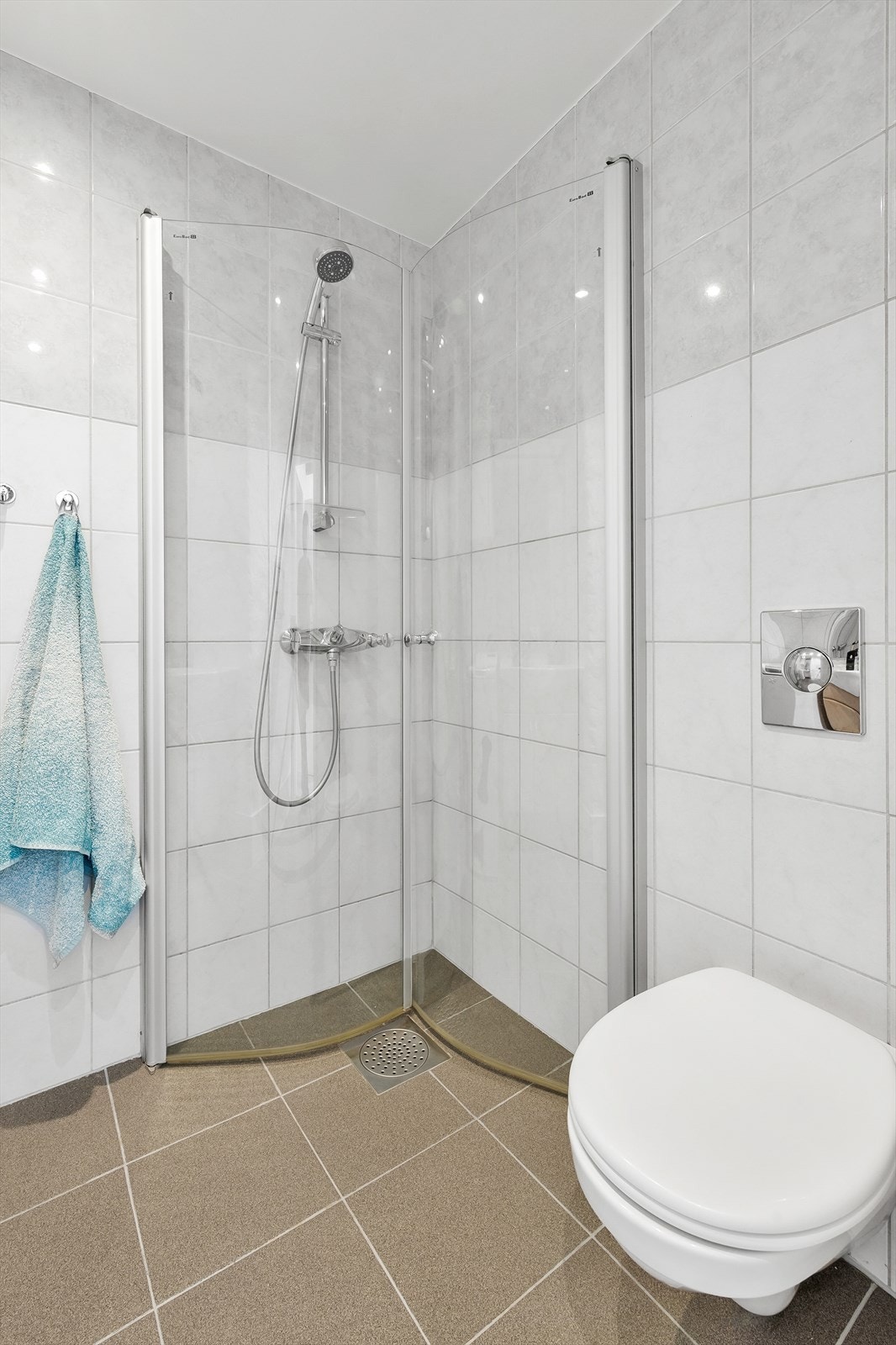 Bade består av vegghengt toalett, servant med underskaper, innfellbare dusjdører og opplegg til vaskemaskin. Galleribilde