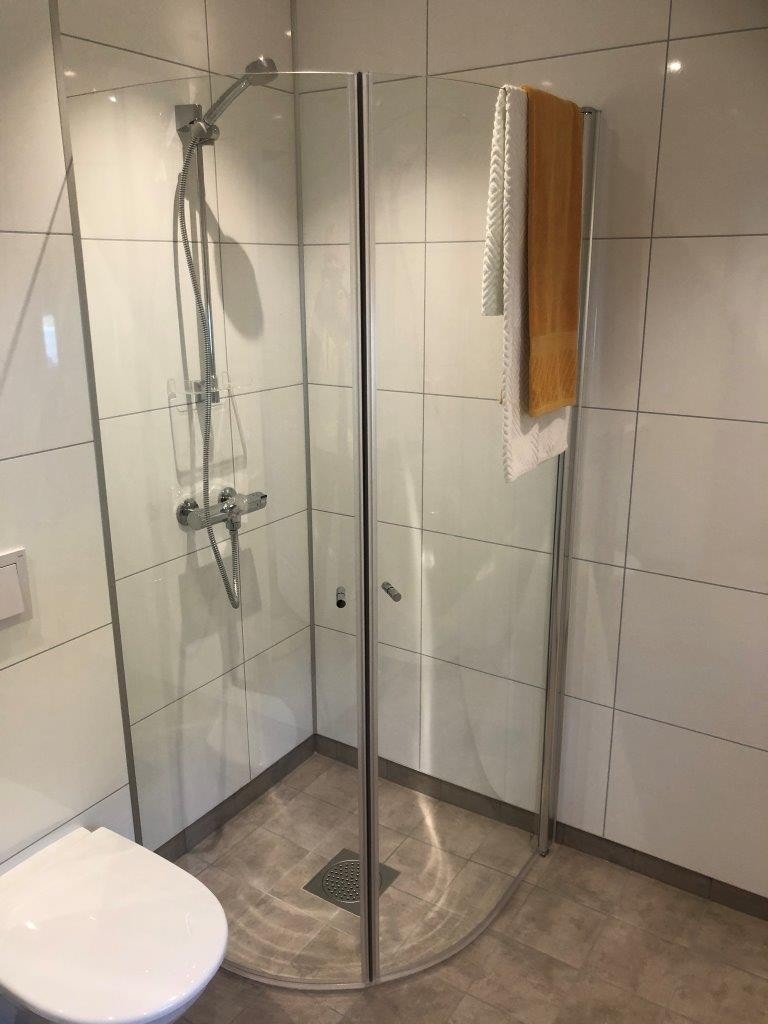 Lyst og trivelig bad med servant-og speilskap, vegghengt toalett og svingbare dusjdører. Galleribilde