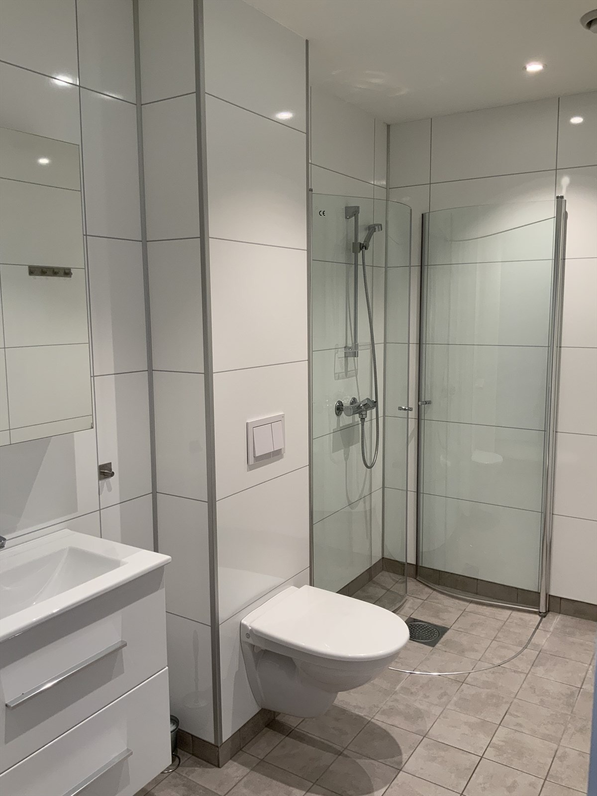 Lyst og trivelig bad med servant-og speilskap, vegghengt toalett og svingbare dusjdører. Galleribilde