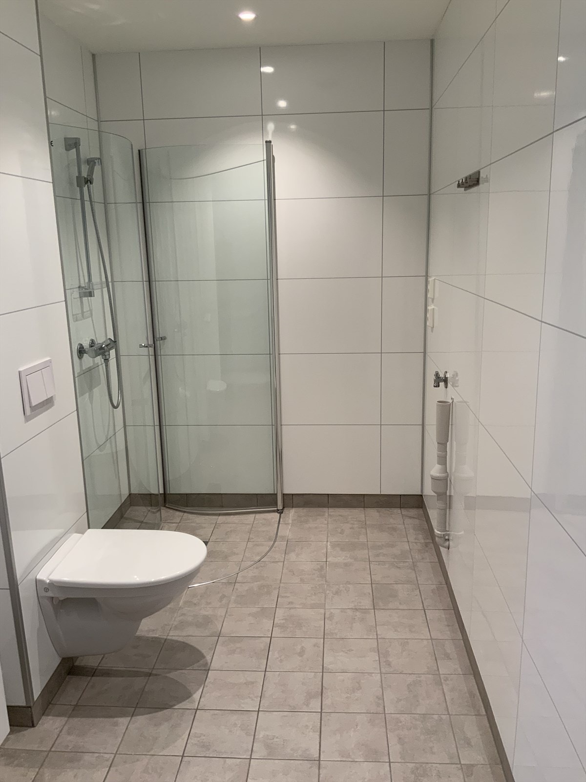 Lyst og trivelig bad med servant-og speilskap, vegghengt toalett og svingbare dusjdører. Galleribilde