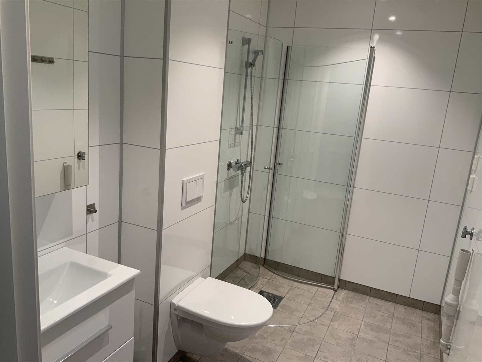 Lyst og trivelig bad med servant-og speilskap, vegghengt toalett og svingbare dusjdører. Galleribilde