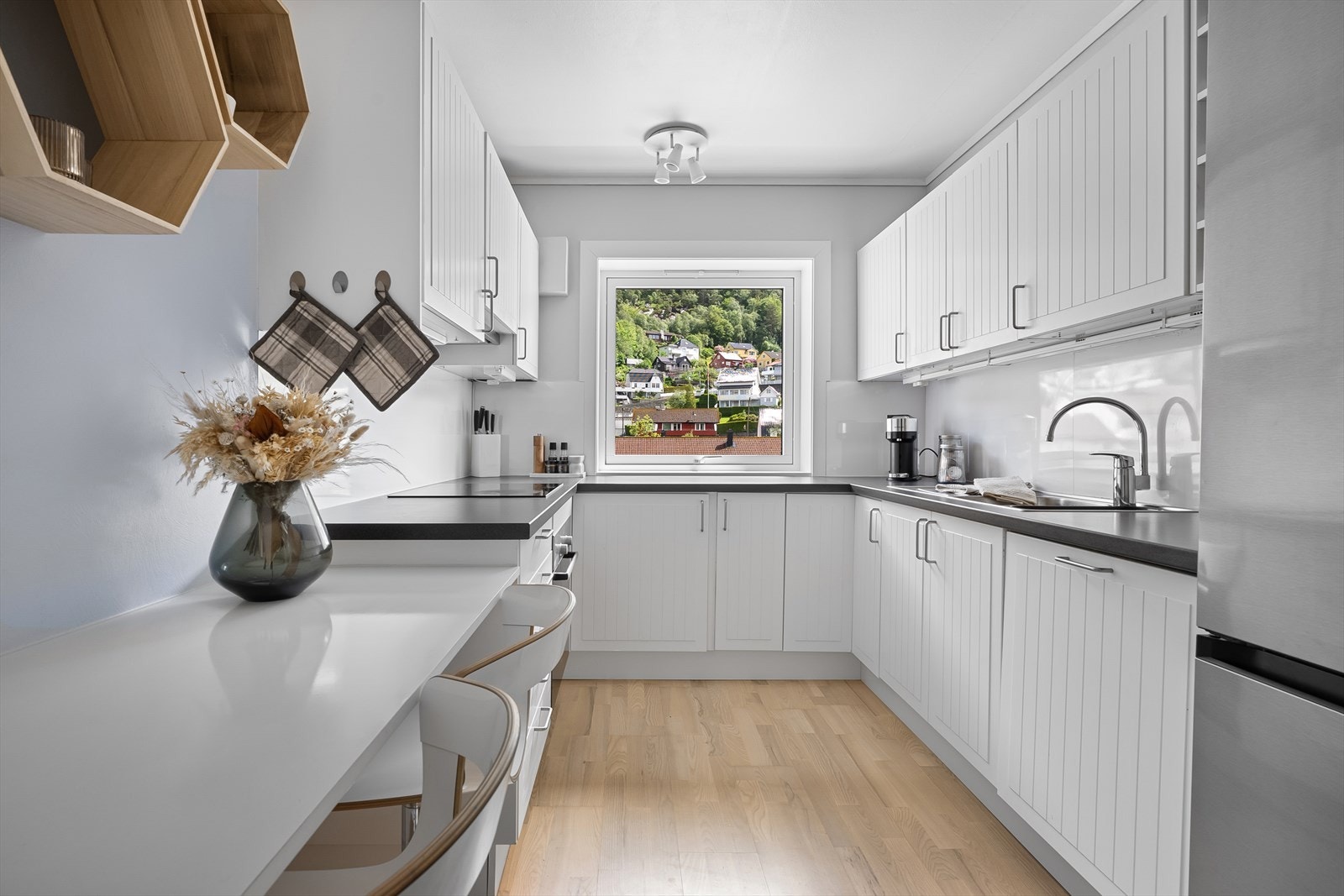 Pent kjøkken med hvite fronter og integrerte hvitevarer Galleribilde