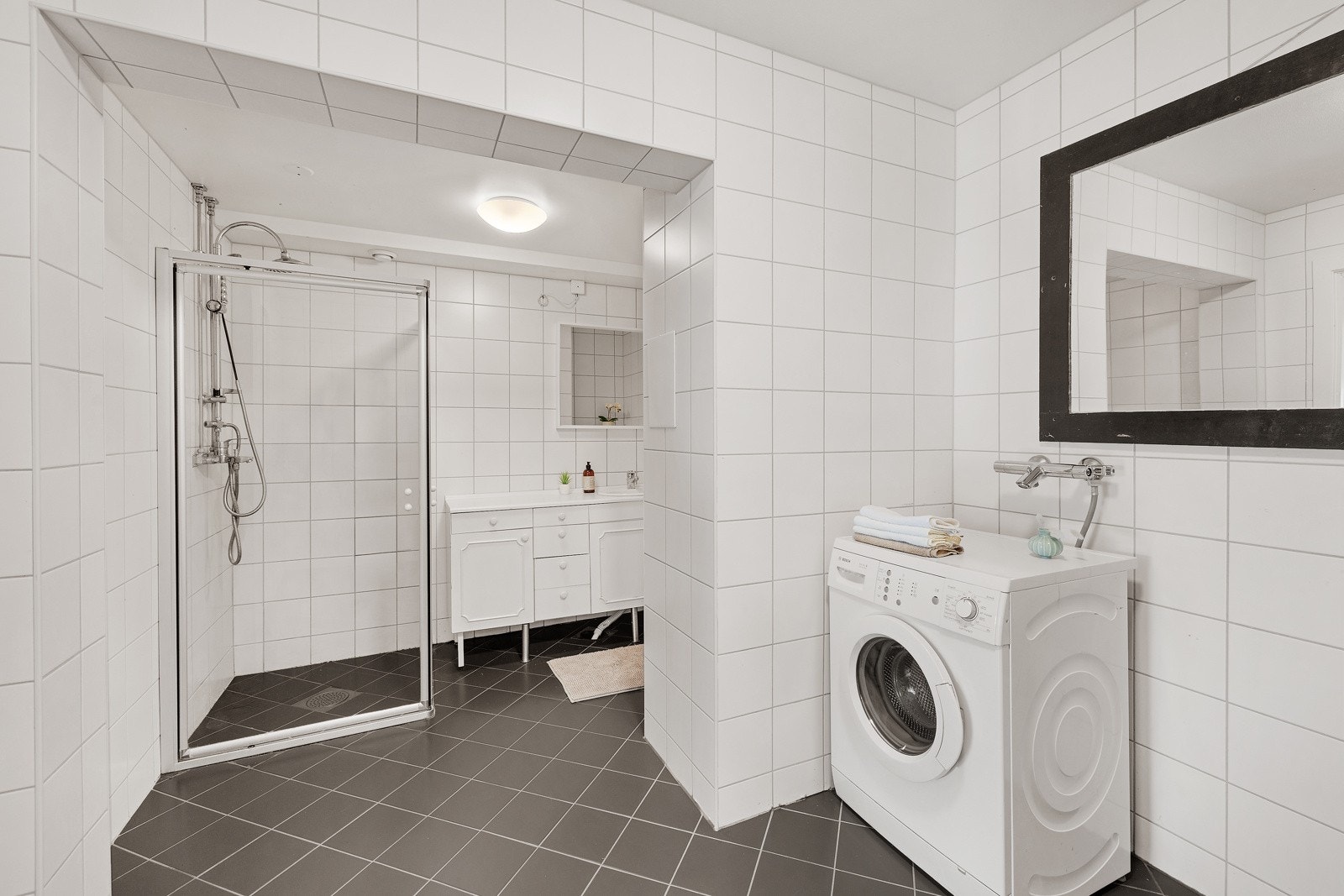 Det er eget dusjhjørne, vegghengt toalett og servantinnredning med skap på badet Galleribilde