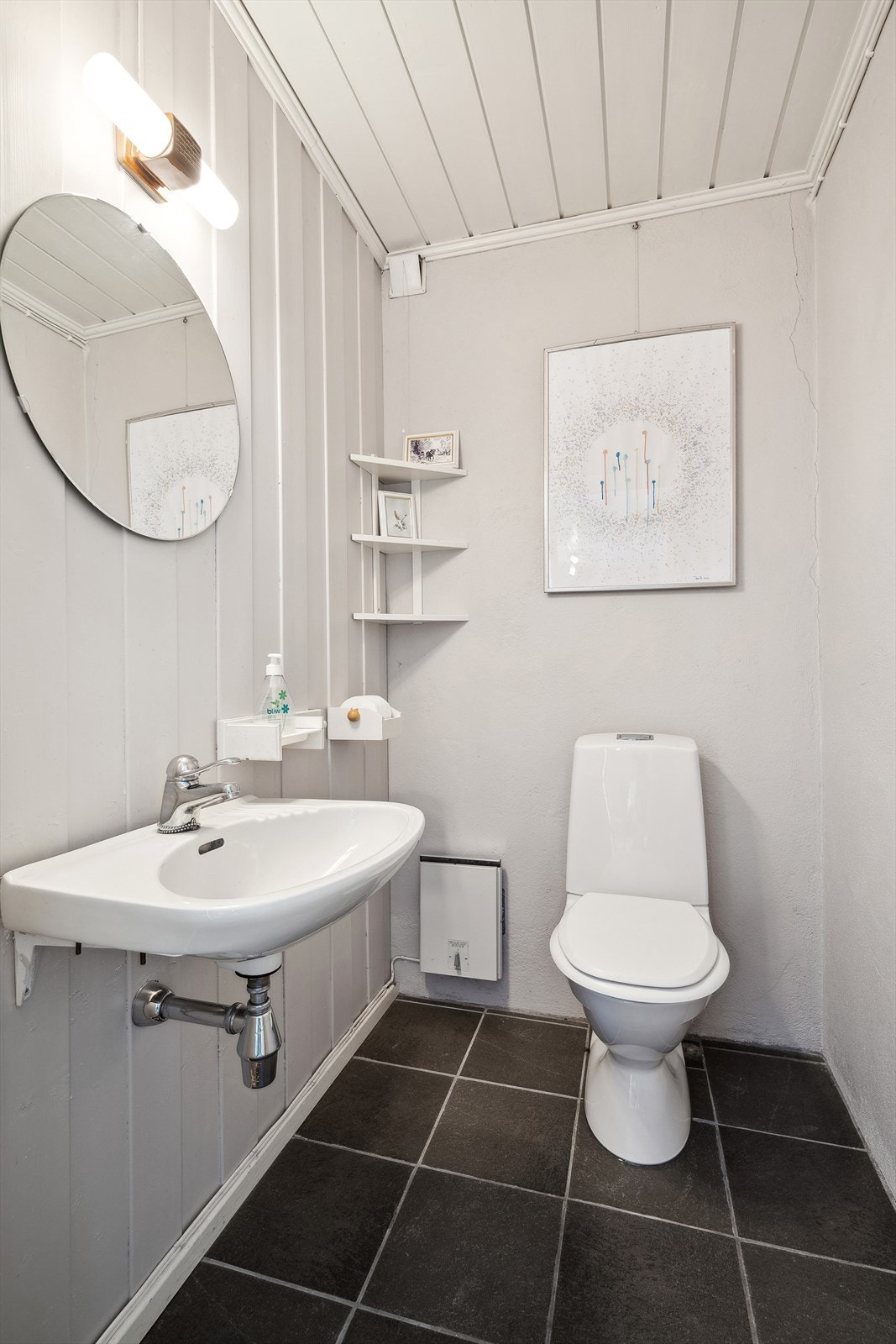 I underetasjen er det et praktisk separat toalettrom med flislagt gulv og malte vegger. Rommet er utstyrt med servant, speil og toalett. Galleribilde