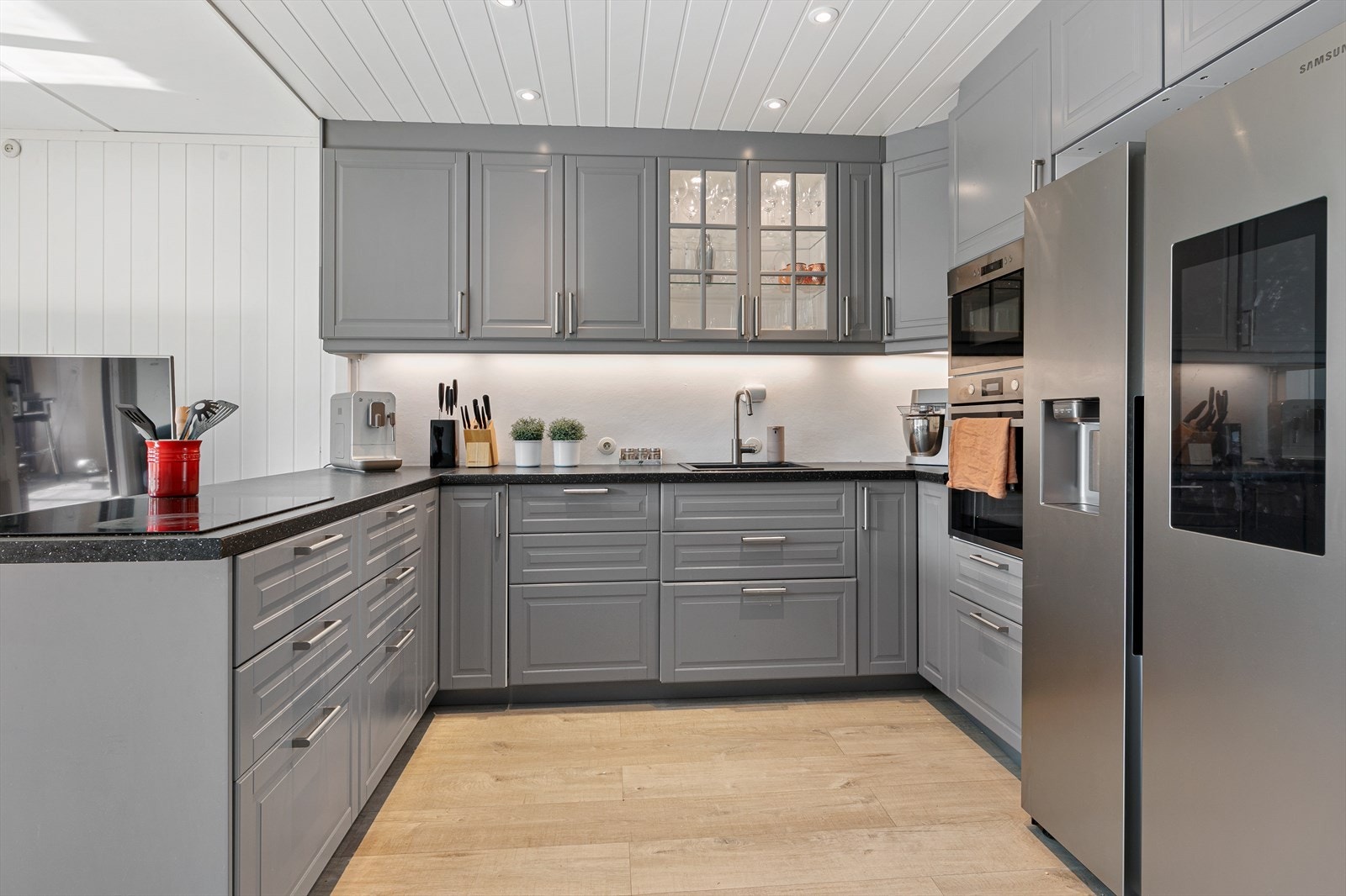 Kjøkkenet ble satt inn i 2019 og harmonerer fint i det eller store og lyse rommet. Selve innredningen er fra IKEA og har grå, profilerte fronter og laminat benkeplate. Av hvitevarer følger koketopp, stekeovn. Mikro og oppvaskmaskin. Galleribilde
