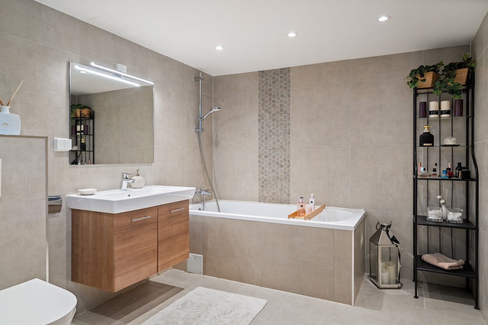 Vegghengt toalett, servant med underskap, vegghengt skap ved døren og badekar som både små og store vil sette pris på. Galleribilde