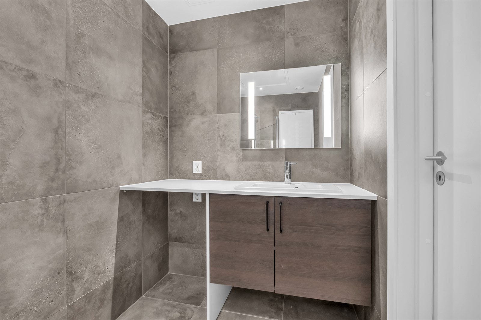 Lekkert fliselagt bad. Servant med skapinnredning. Opplegg for vaskemaskin. Galleribilde