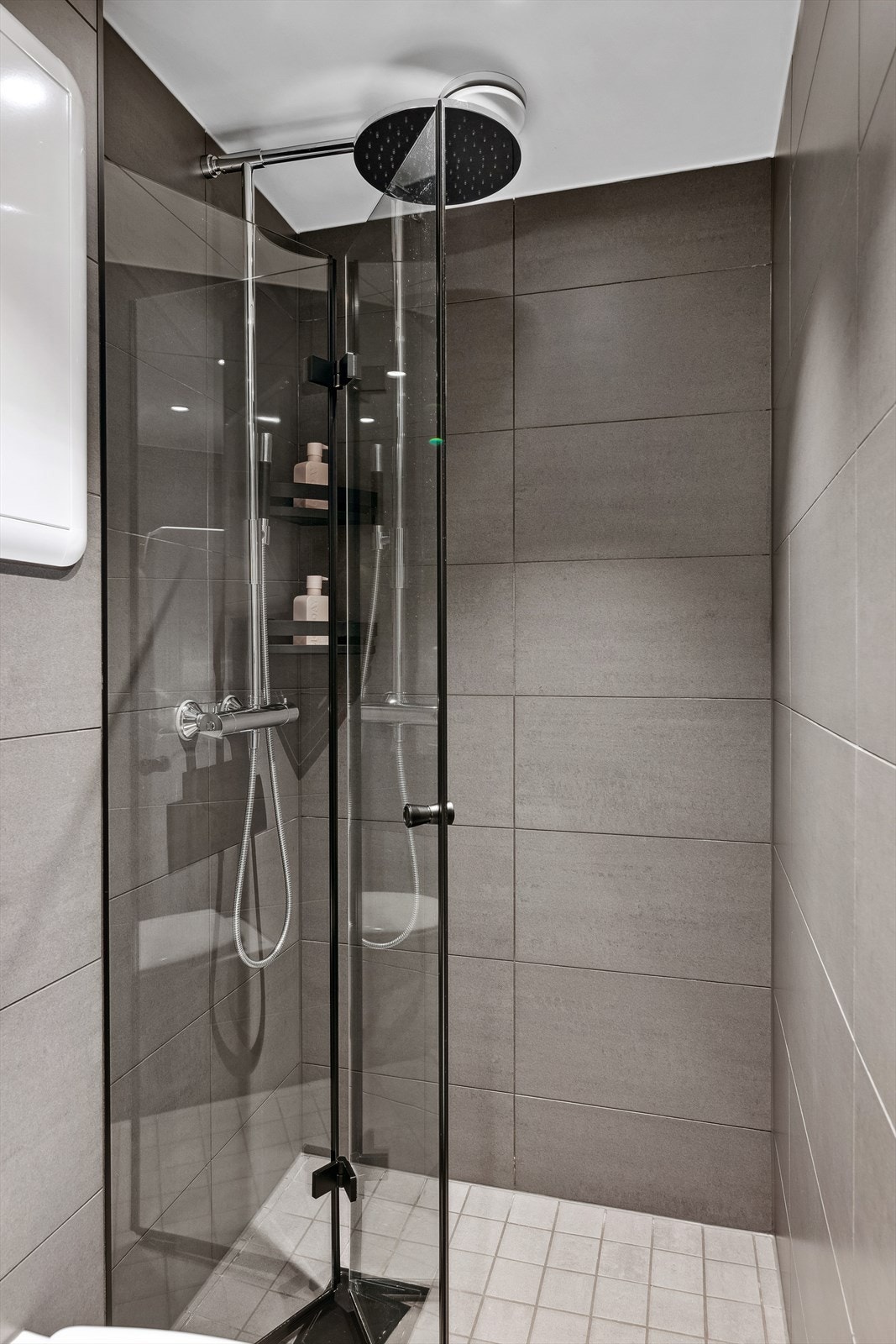 Badet er innredet med servantskap med ettgrepsblandebatteri, speil med lys, høyskap, avskjermet dusjhjørne med glassdører, blandebatteri og dusjgarnityr. Galleribilde