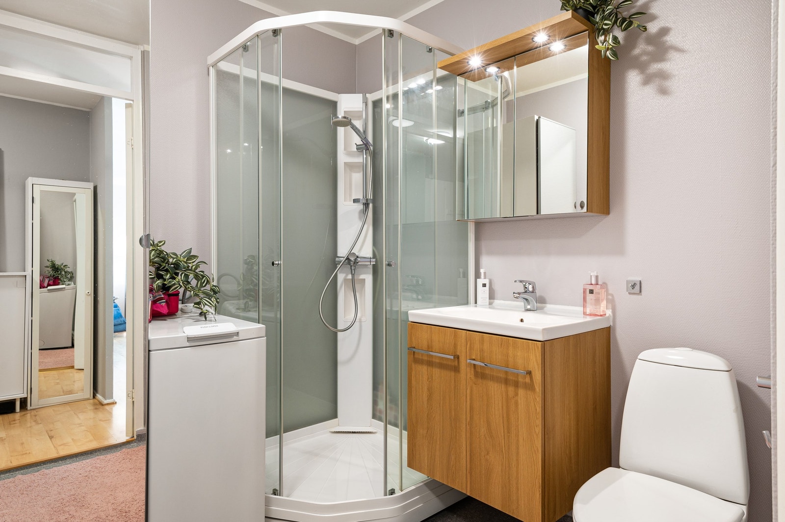 Badet er pent innredet med servantskap med overskap og speil med lys, dusjkabinett, toalett og opplegg for vaskemaskin. Galleribilde