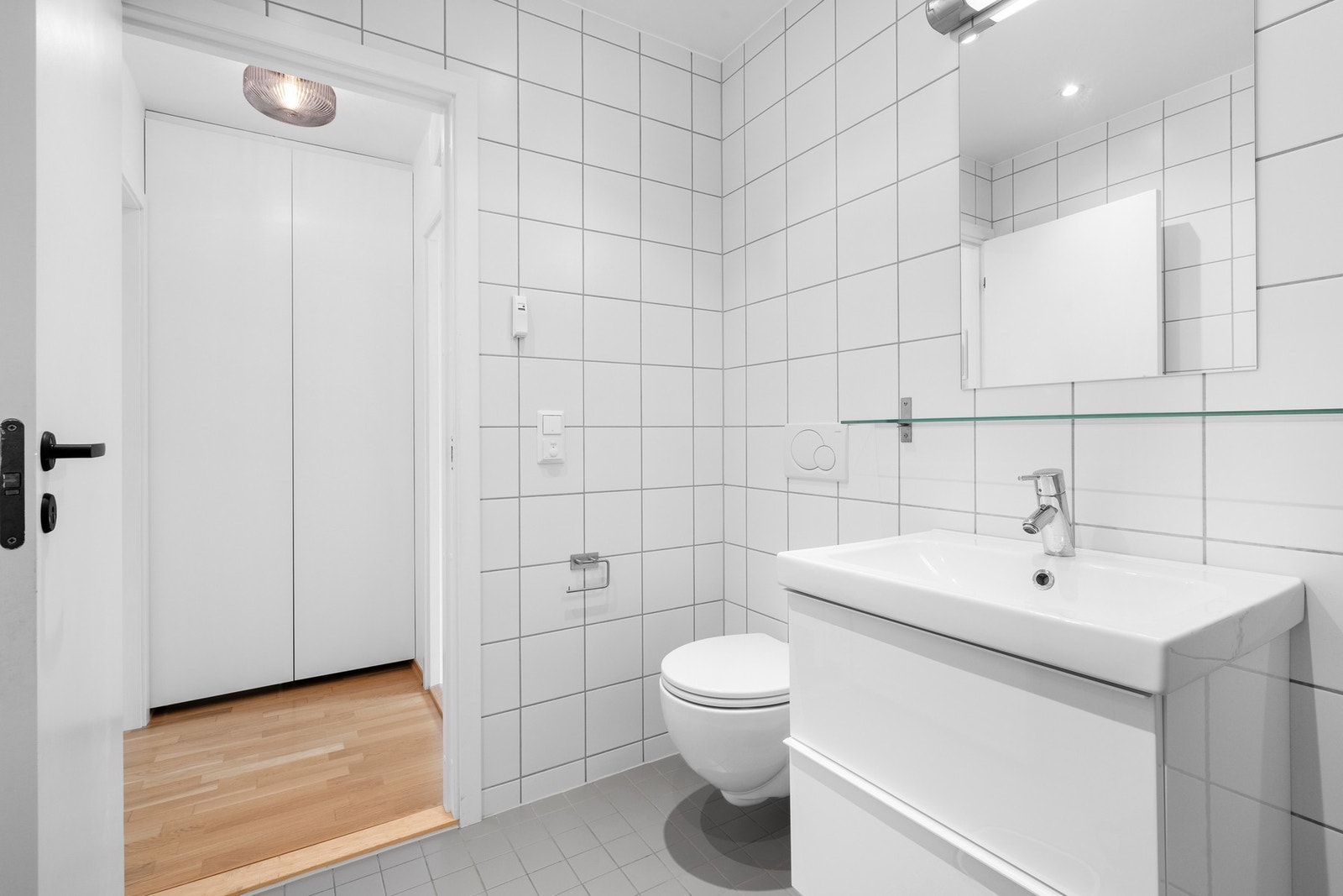 Badet er innredet med servant på skuffeinnredning, speil, vegghengt toalett og dusjnisje. Galleribilde