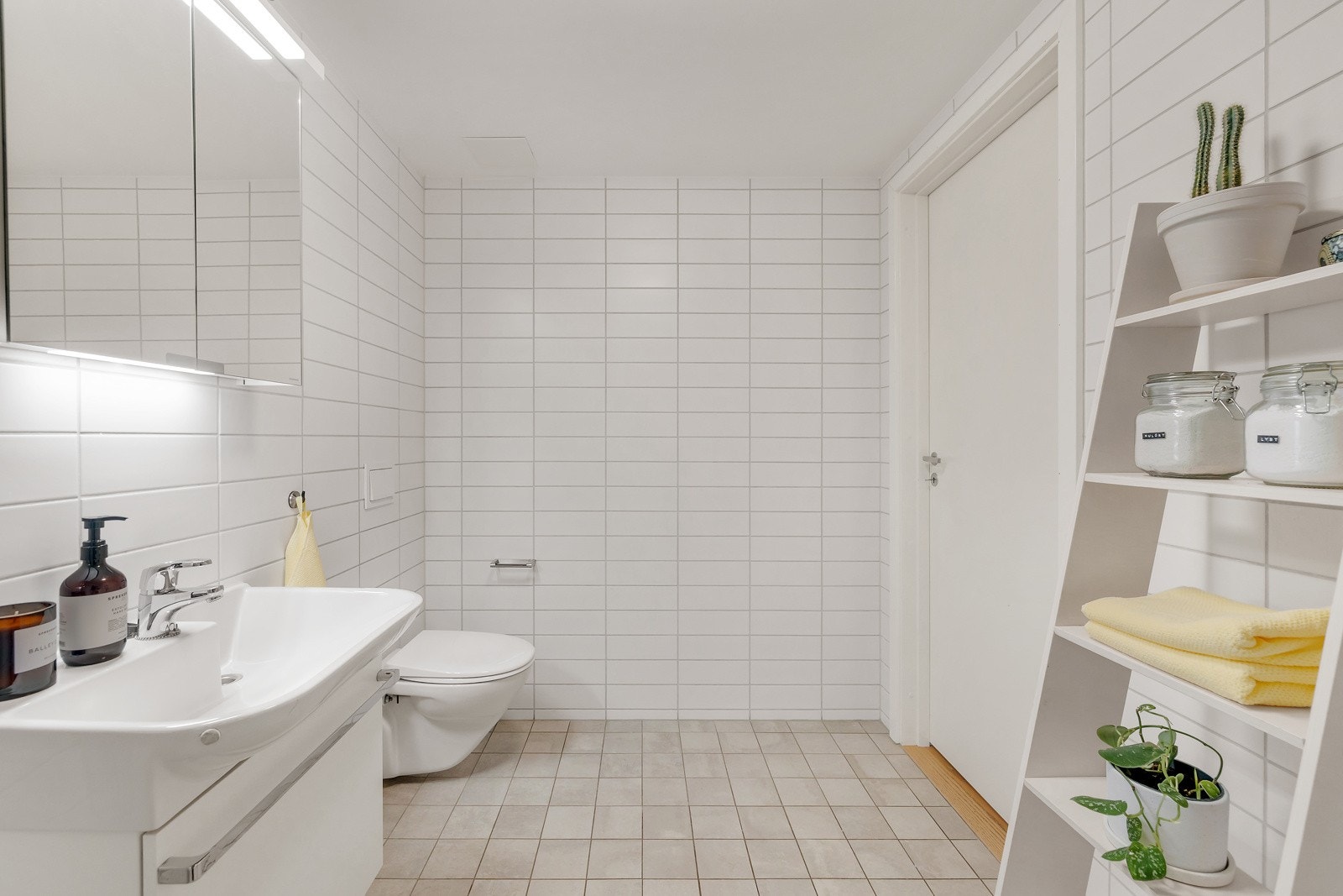 Moderne baderomsinnredning med skuff og heldekkende servant, speilskap med belysning over. Galleribilde