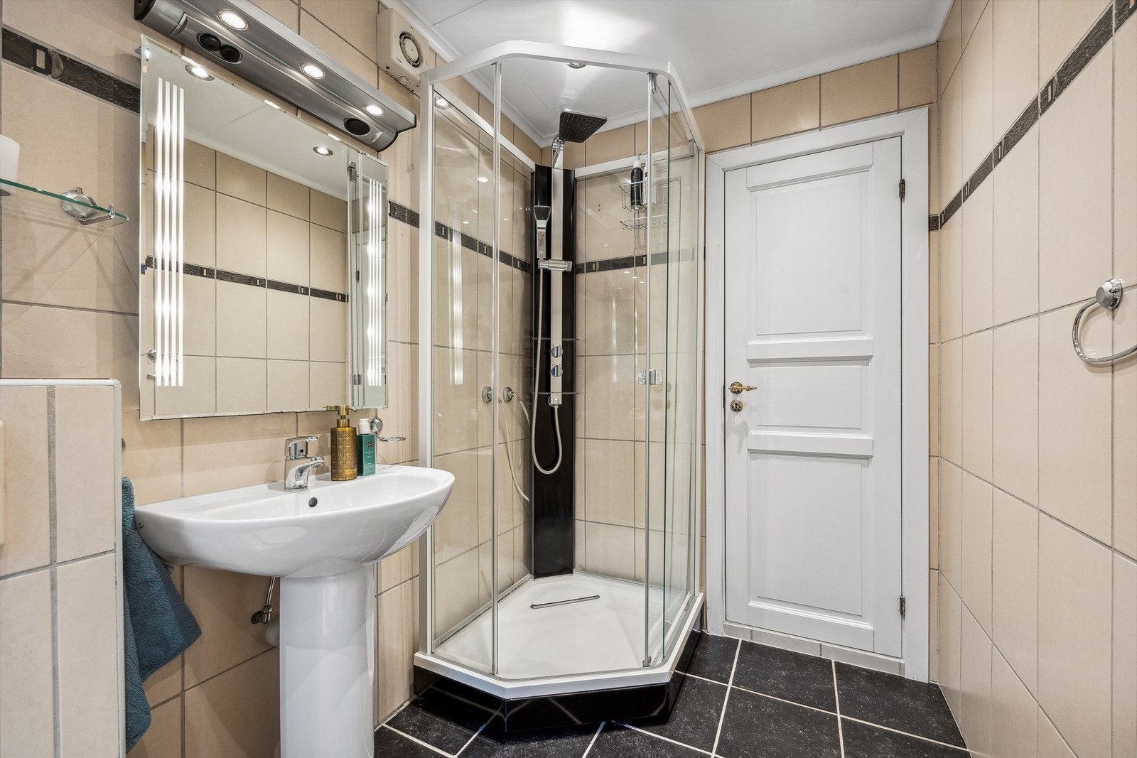 Flislagte overflater og innredet med søylevask, speil med belysning, dusjkabinett, vegghengt toalett og opplegg for vaskemaskin. Galleribilde