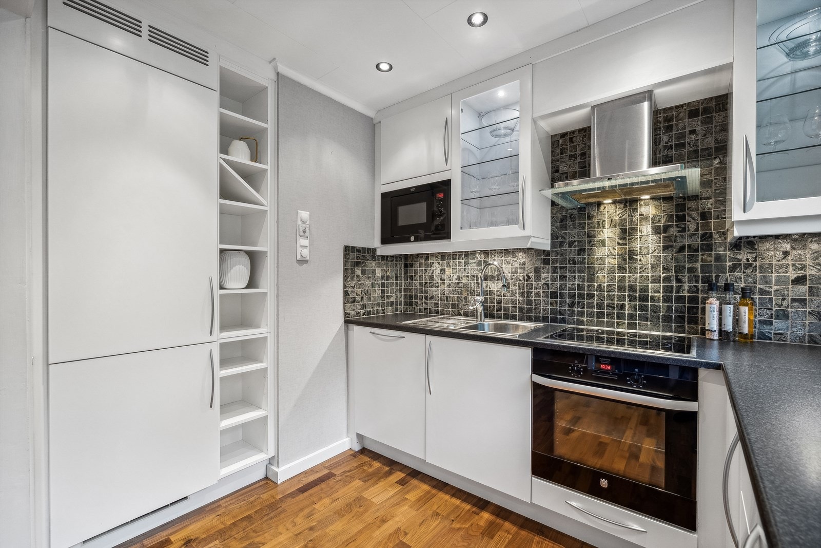 Stilren innredningen av nyrere dato, med slette skapfronter (noen glassfronter med belysning inni) og laminat benkeplate. Galleribilde