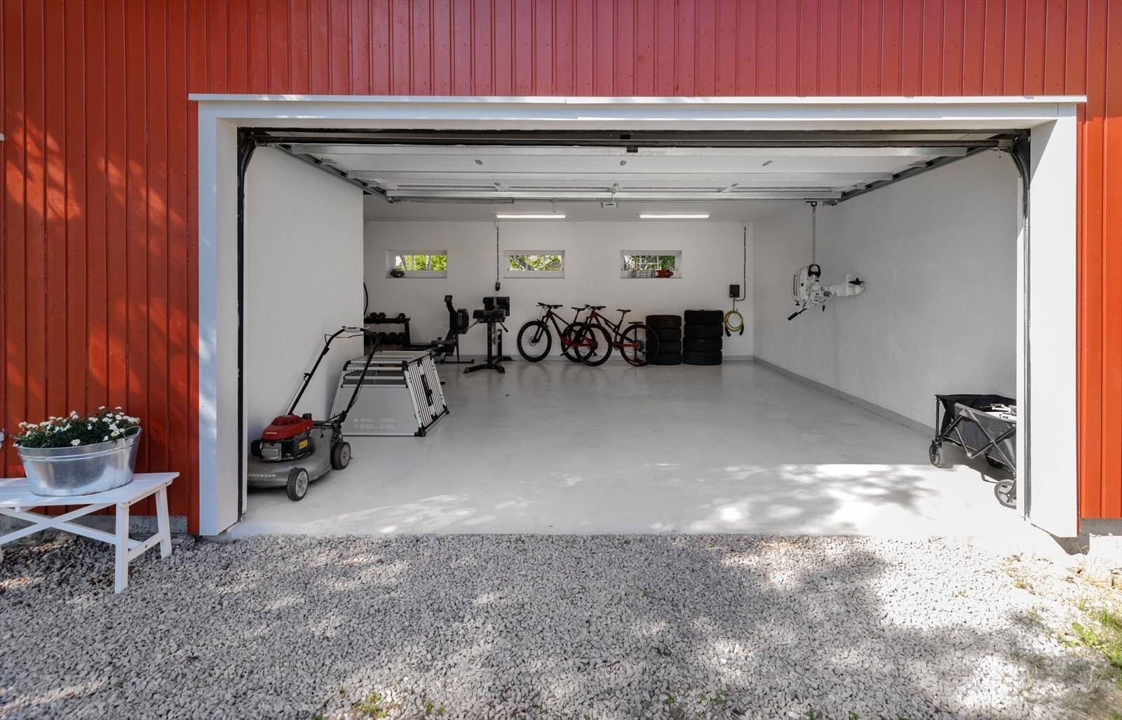 I den romslige garasjen er det plass til to biler, og man kan for eksempel anrette et treningsrom. Her er det en manuell løpekatt til oppheng av f.eks båtmotorer. Galleribilde