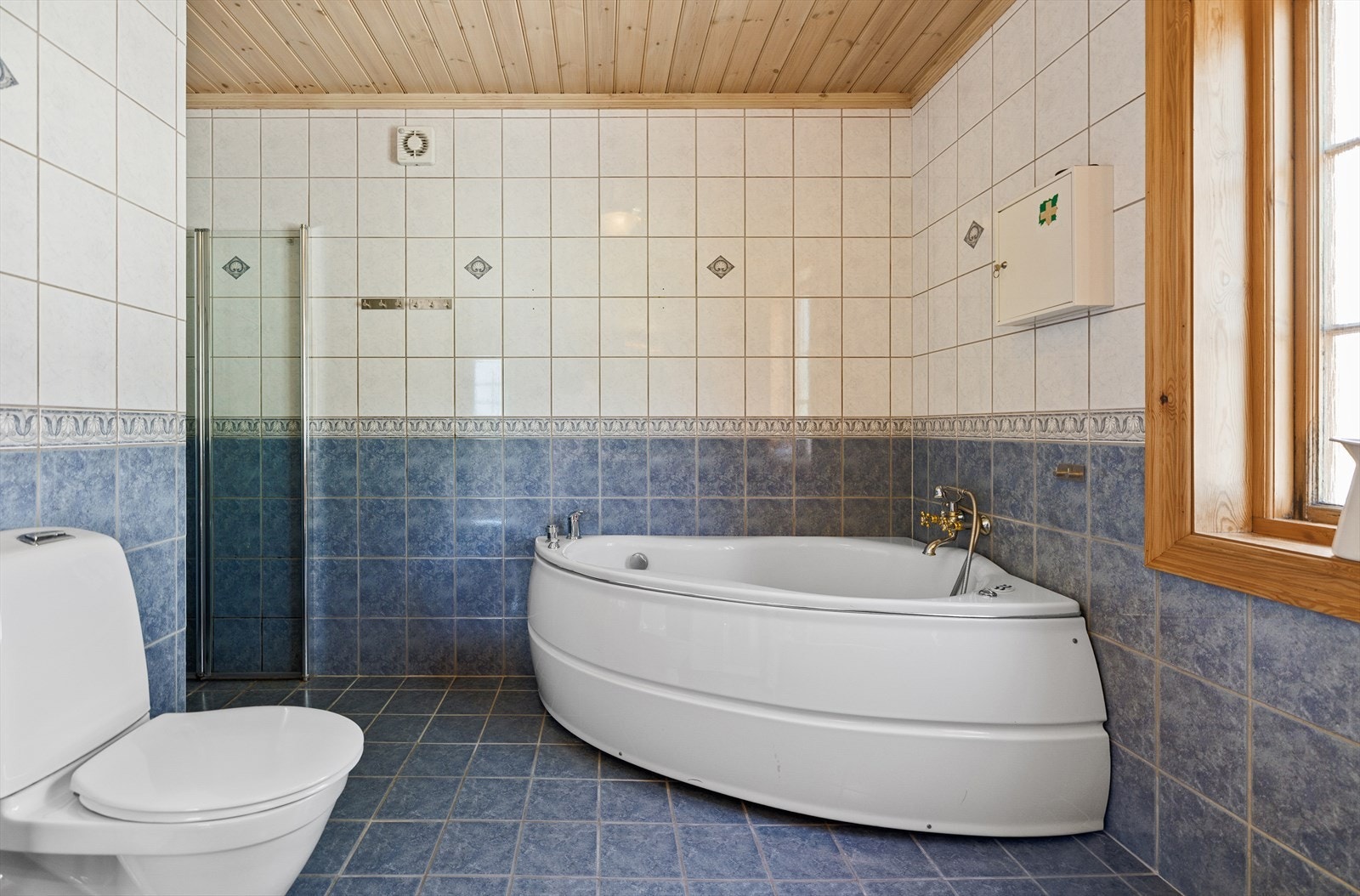 Hvitt og blått mot dypbrunt treverk _ badet hører fint hjemme i boligen. Galleribilde