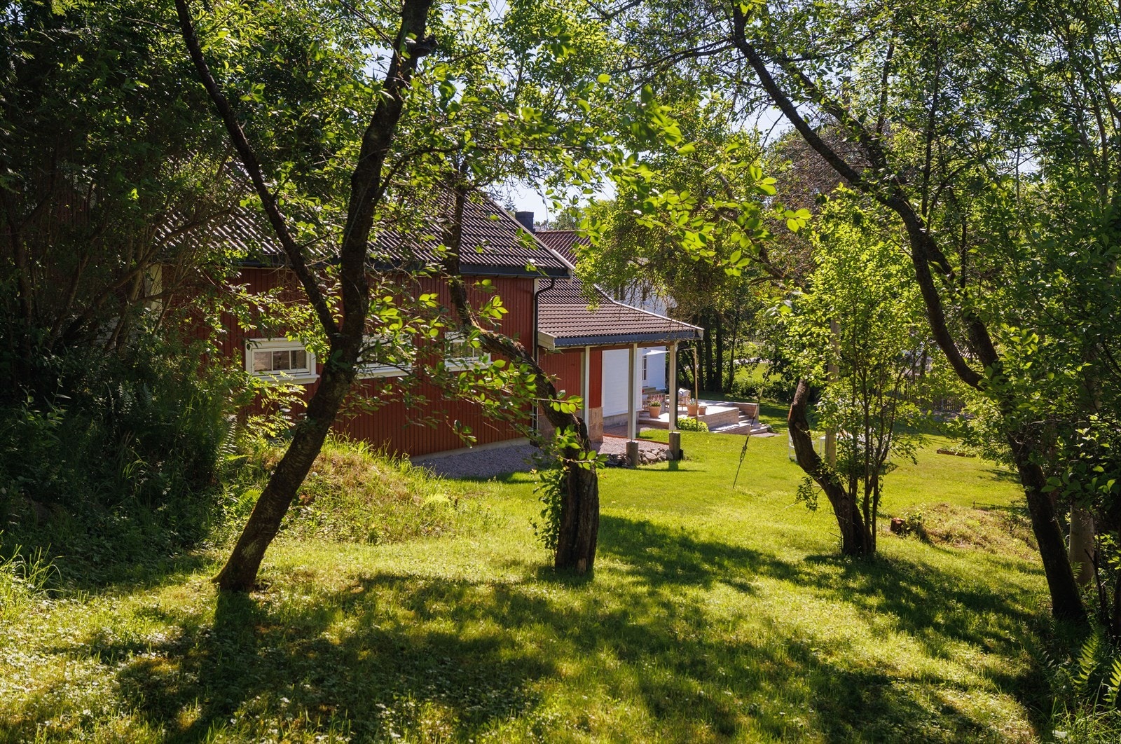 Tomten strekker seg bak garasjen og annekset. Her er det gamle fruktrær som viser spor etter levd liv. Galleribilde