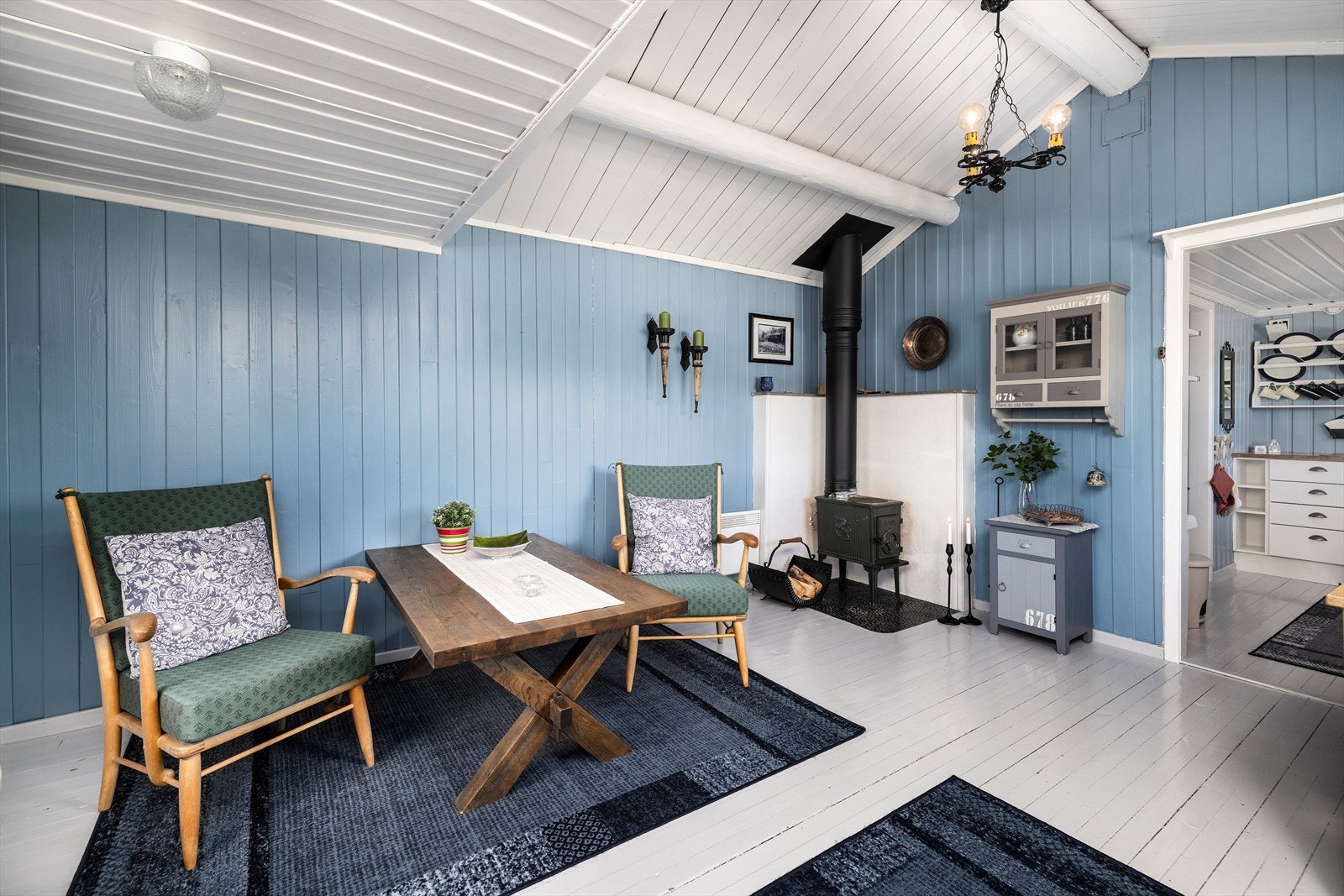 Stue med delvis røstet himling. panelovn og vedovn med stålpipe varmer kjapt opp rommet. Galleribilde