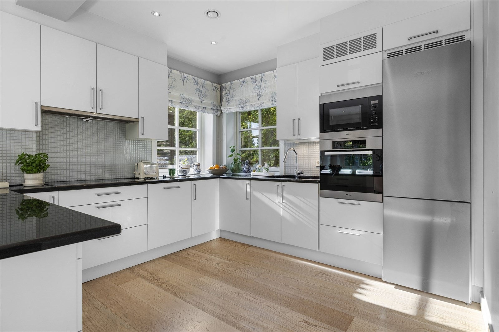 Benkeplater i sort granitt. Nedfelt oppvaskkum i sort kompositt. Integrerte hvitevarer fra Miele Galleribilde