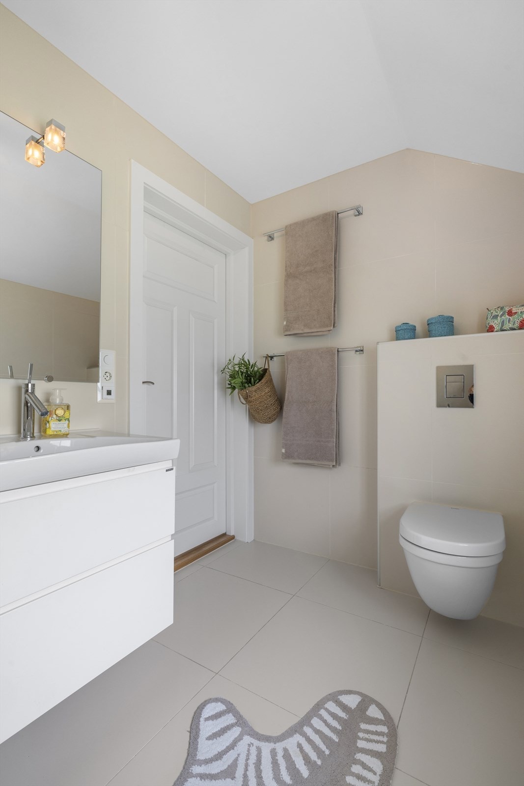 Pent bad/wc med støpt flislagt gulv over varmekabler. Flislagte vegger og malt himling med innfelte downlights. Galleribilde