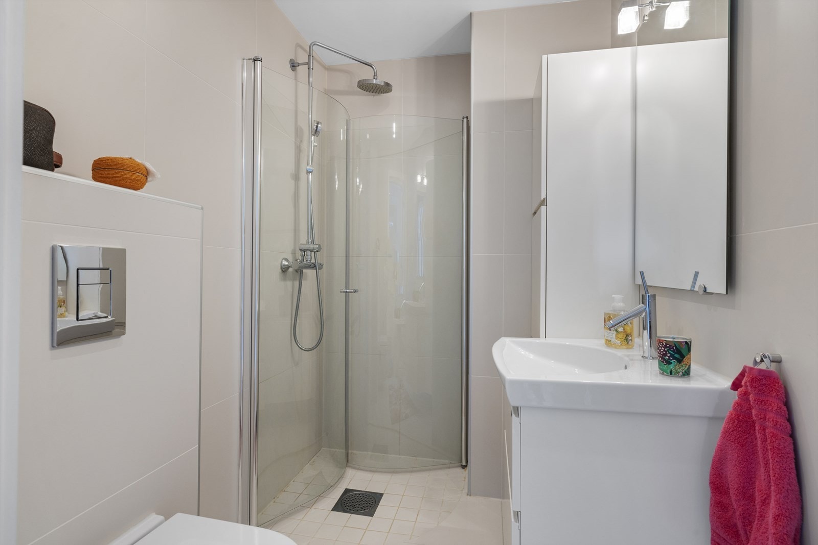 Delikat dusjbad/wc med støpt flislagt gulv. Flislagte vegger og malt himling med innfelte downlights. Badet har innredning med nedfelt servant, veggmontert toalett og dusjvegger/hjørne Galleribilde