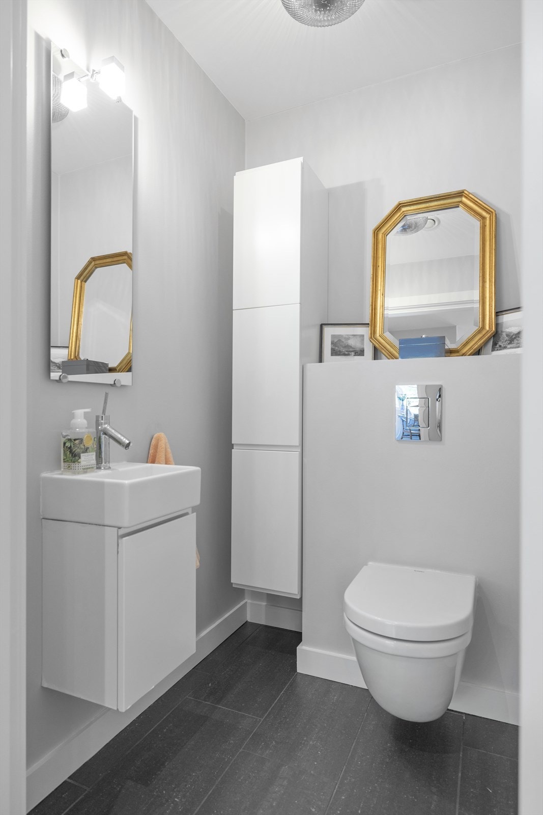 Separat toalettrom med flislagt gulv og malte vegger. Veggmontert toalett med innebygget sisterne. Veggmontert servantskap. Mekanisk avtrekk Galleribilde