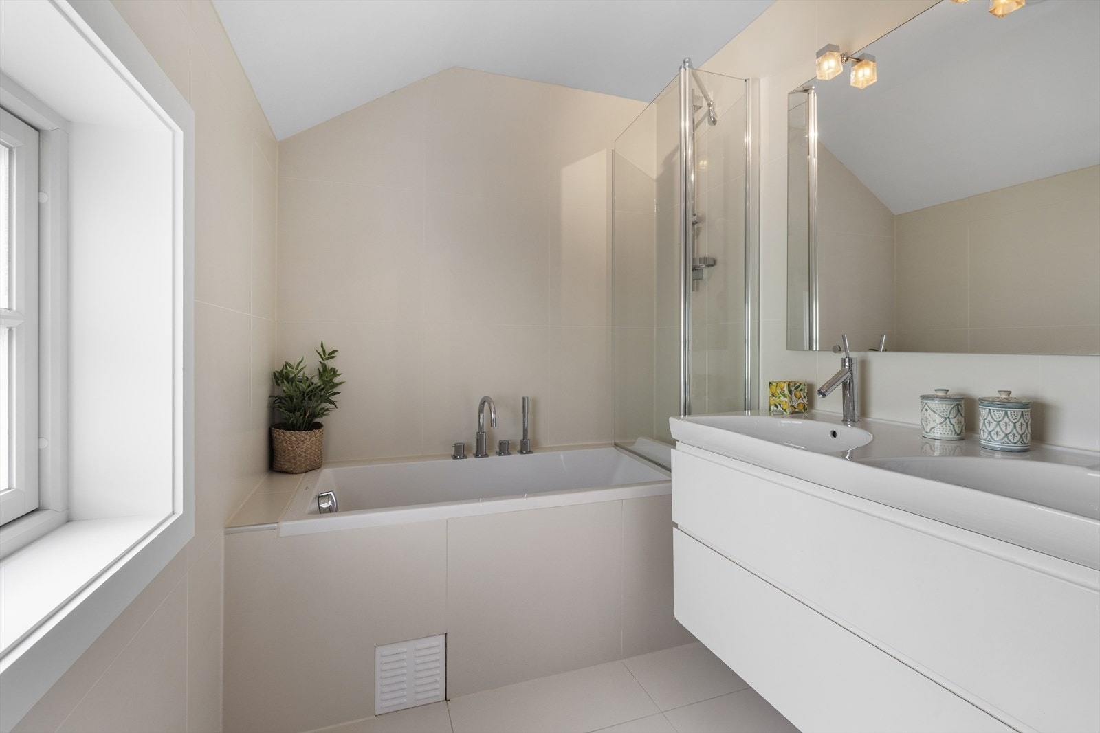 Badet har innredning med to nedfelte servanter, veggmontert toalett og badekar Galleribilde