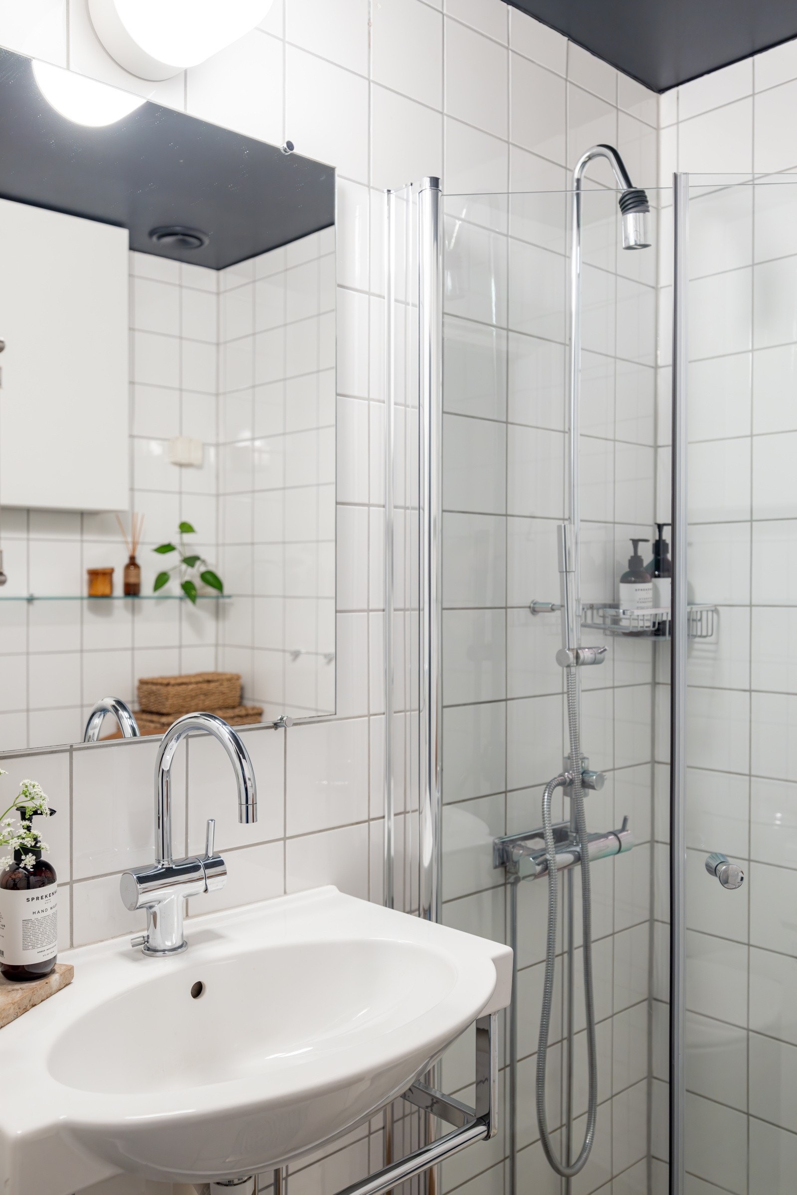 Badet består av veggmontert servant med ett-greps armatur, speil over servant med belysning på vegg, gulvstående toalett, samt dusjnisje med glassdører og ett-greps armatur. Galleribilde