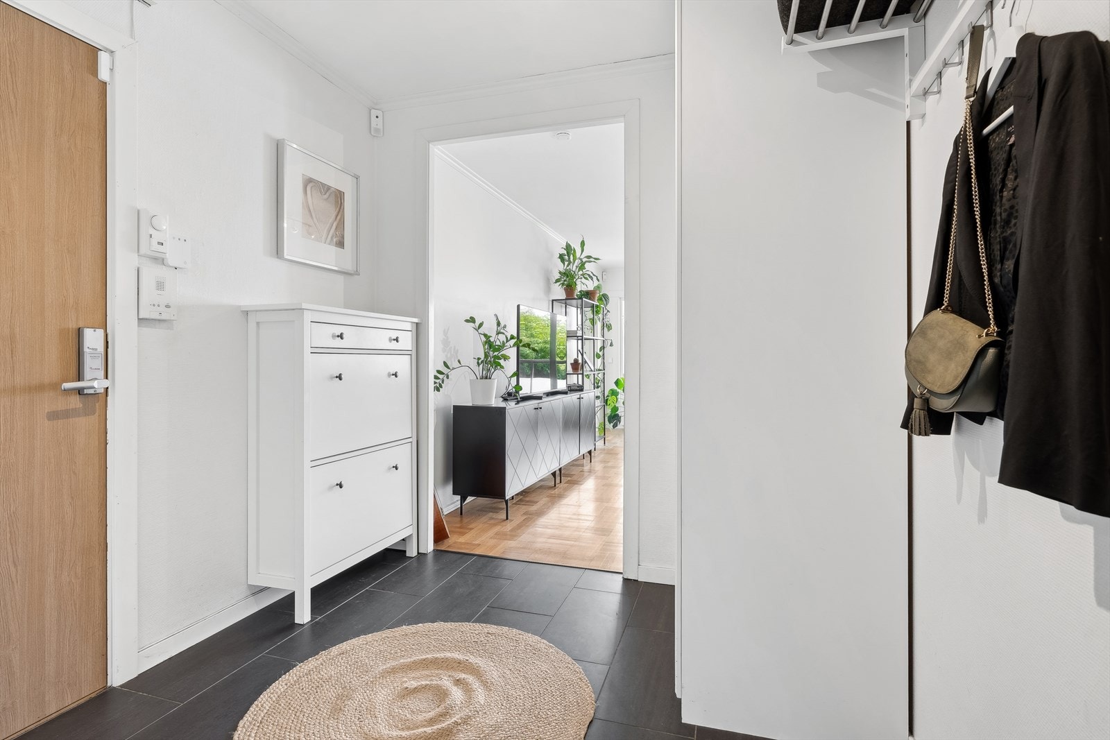 Velkommen inn - En romsli entré med flislagt gulv og garderobeskap til å henge fra seg yttertøy. Galleribilde